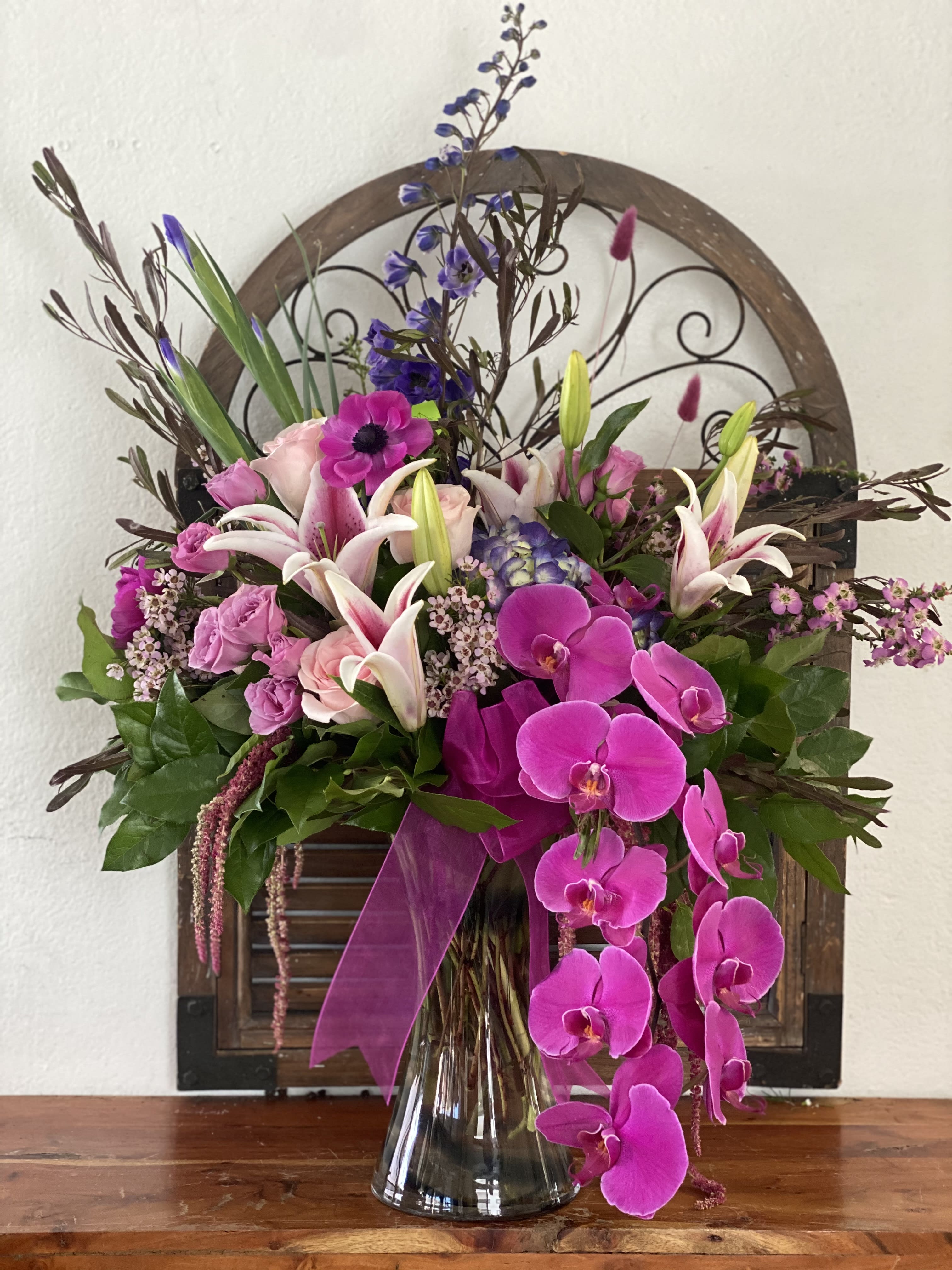 Pink and white floral arrangement in a glass vase with orchids and lilies