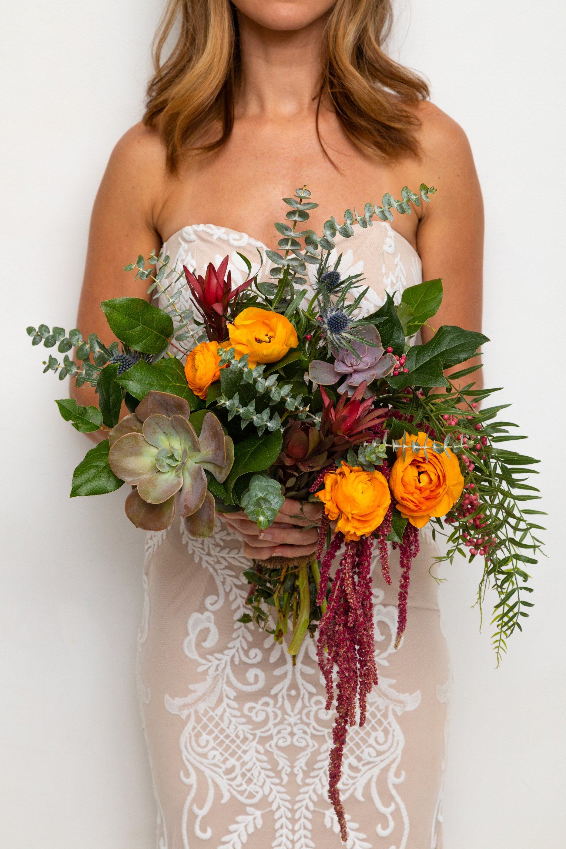 Bride holding a bouquet with orange flowers and succulents