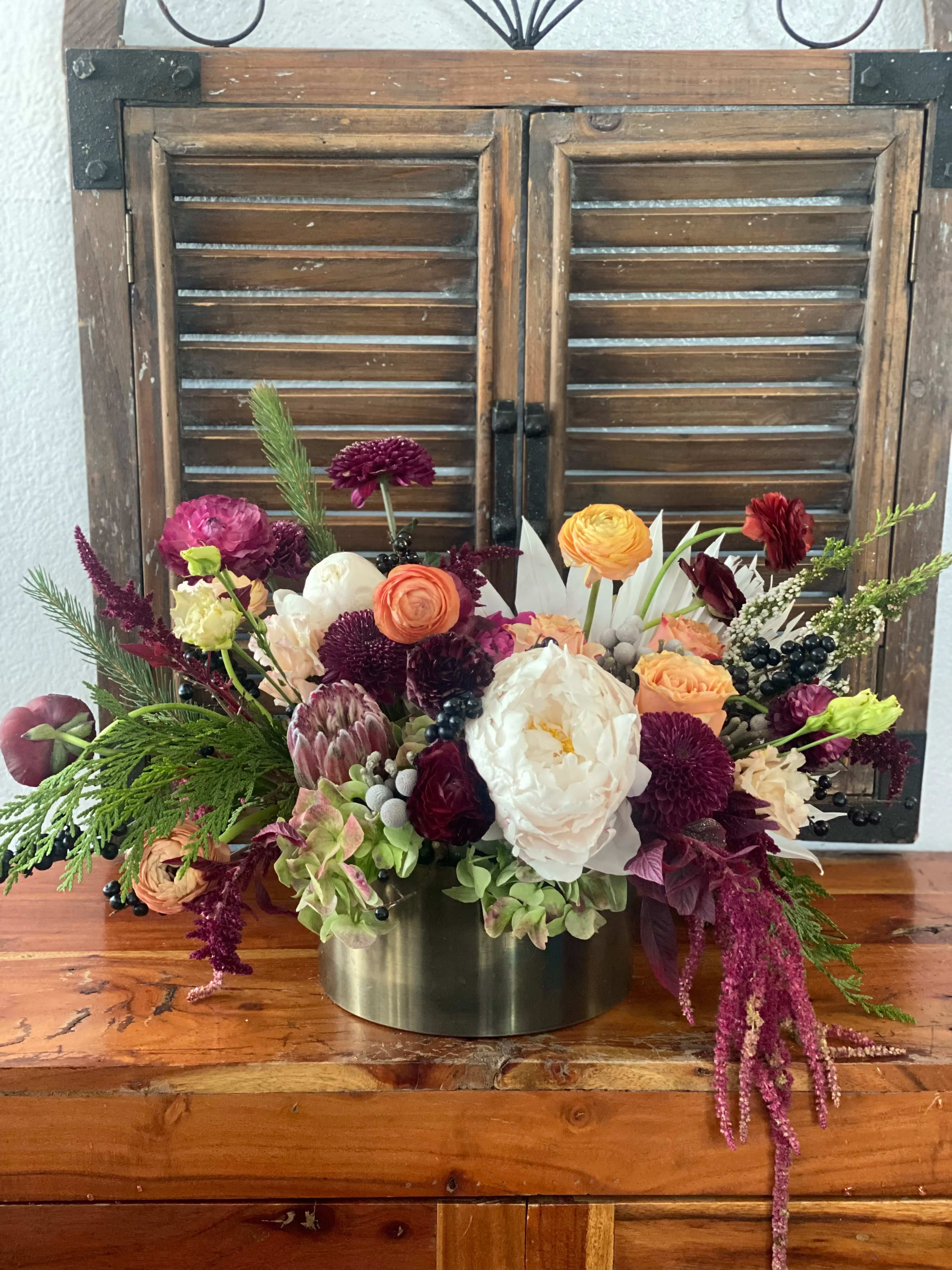 Mixed bouquet of pink, peach, white, and burgundy flowers in a metal vase
