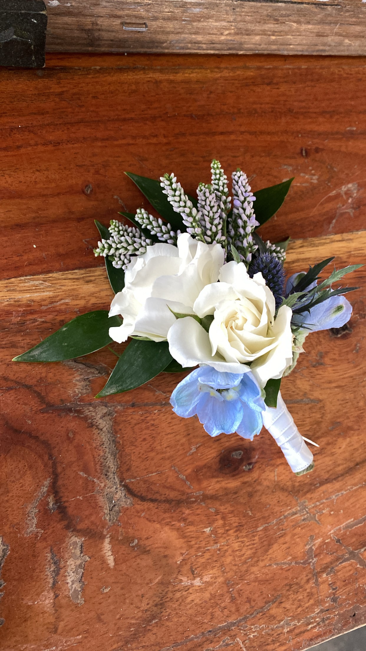 Small white and blue floral boutonniere with ribbon wrap