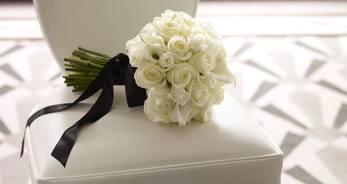 White rose bouquet with black ribbon on a white chair