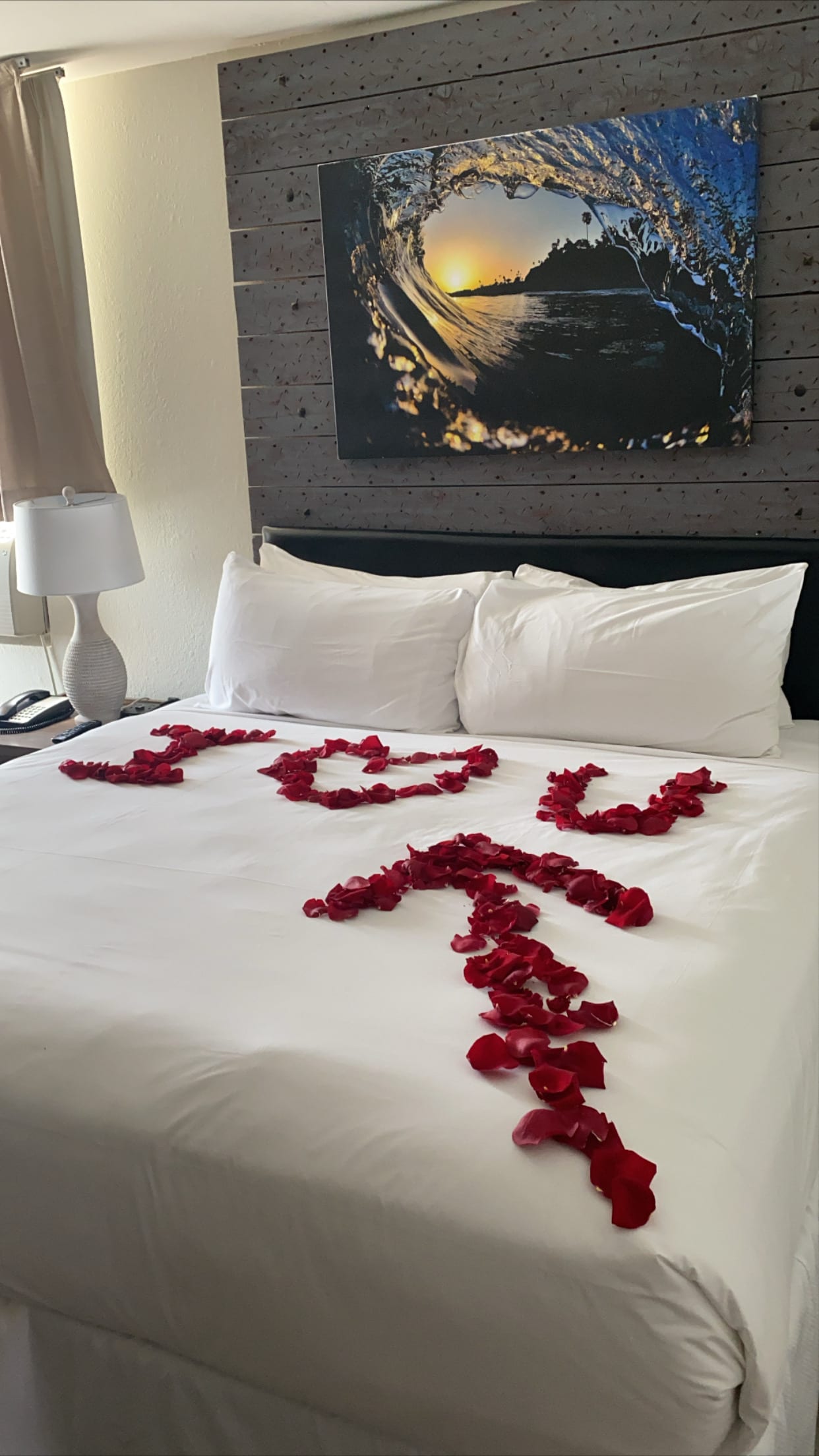 Bed decorated with red rose petals spelling "I LOVE U"