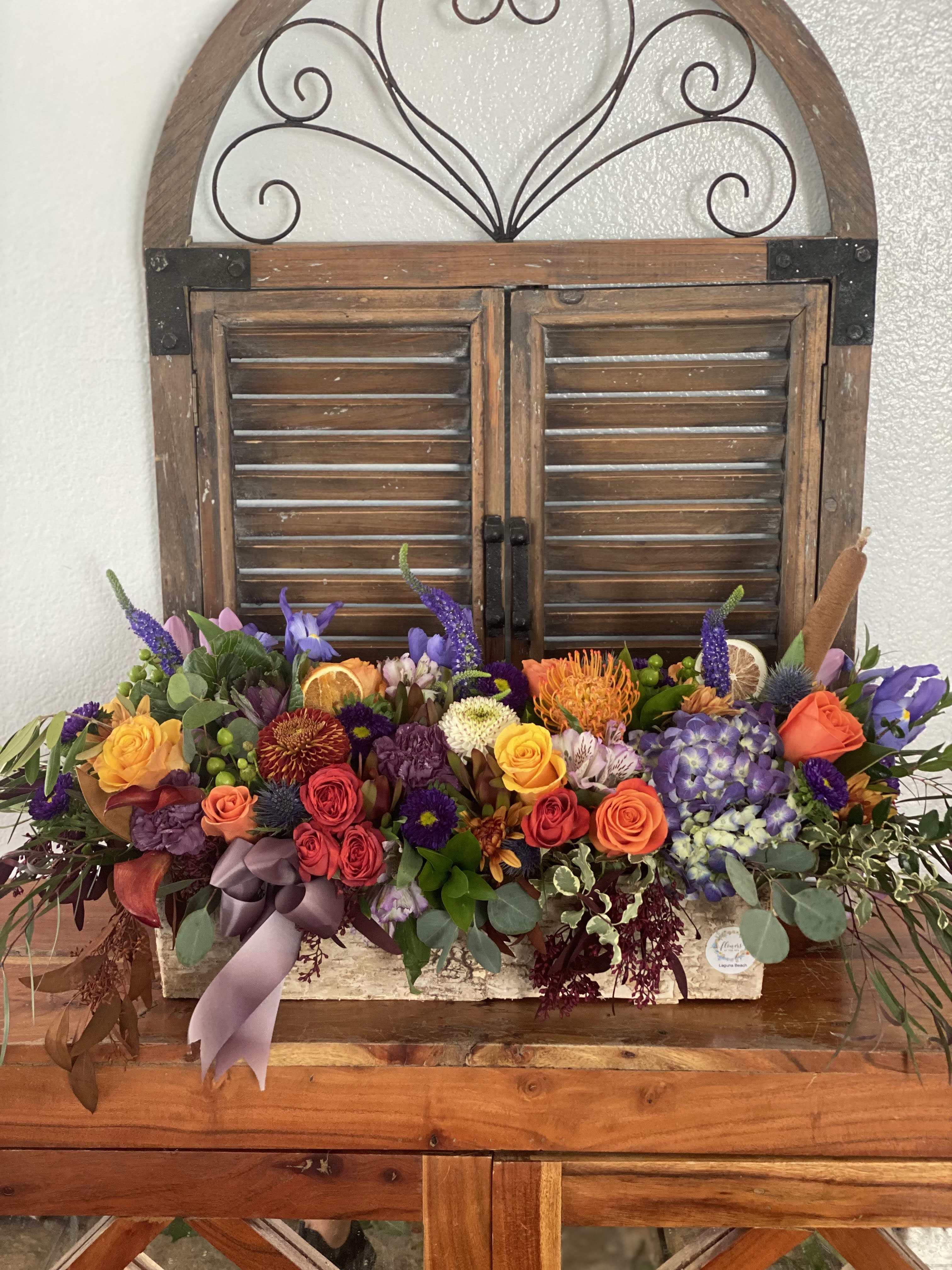 Colorful mixed flower arrangement in a rustic wooden box with a ribbon