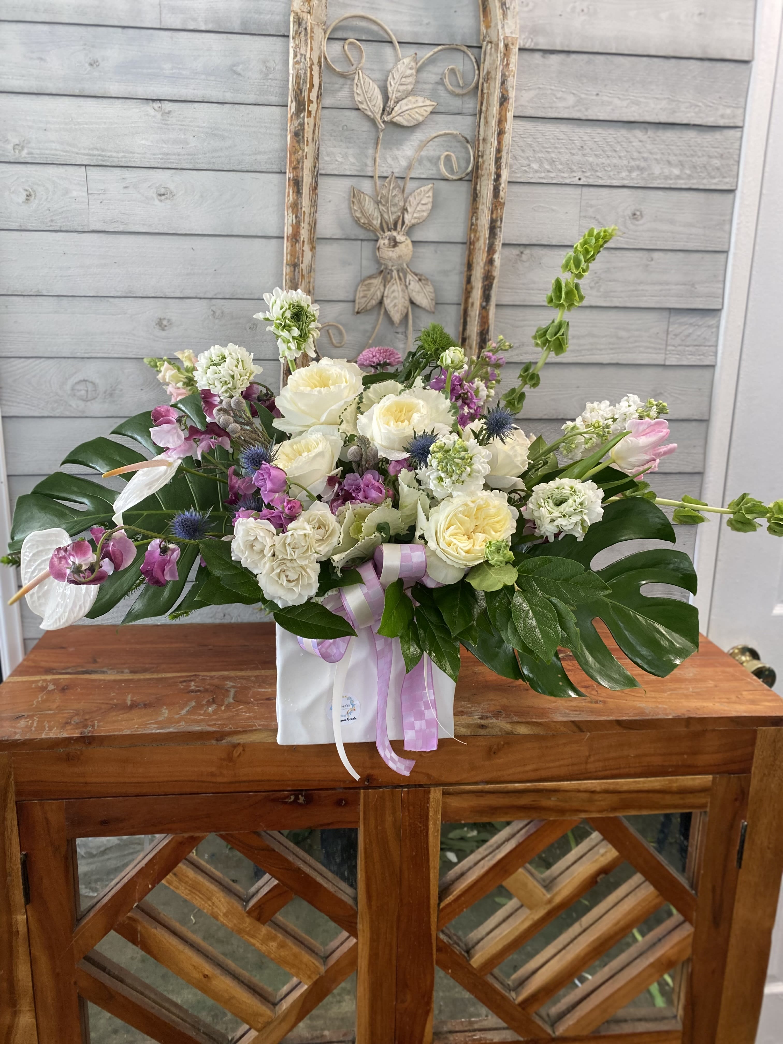 Mixed floral arrangement with white and pink blooms in a white box