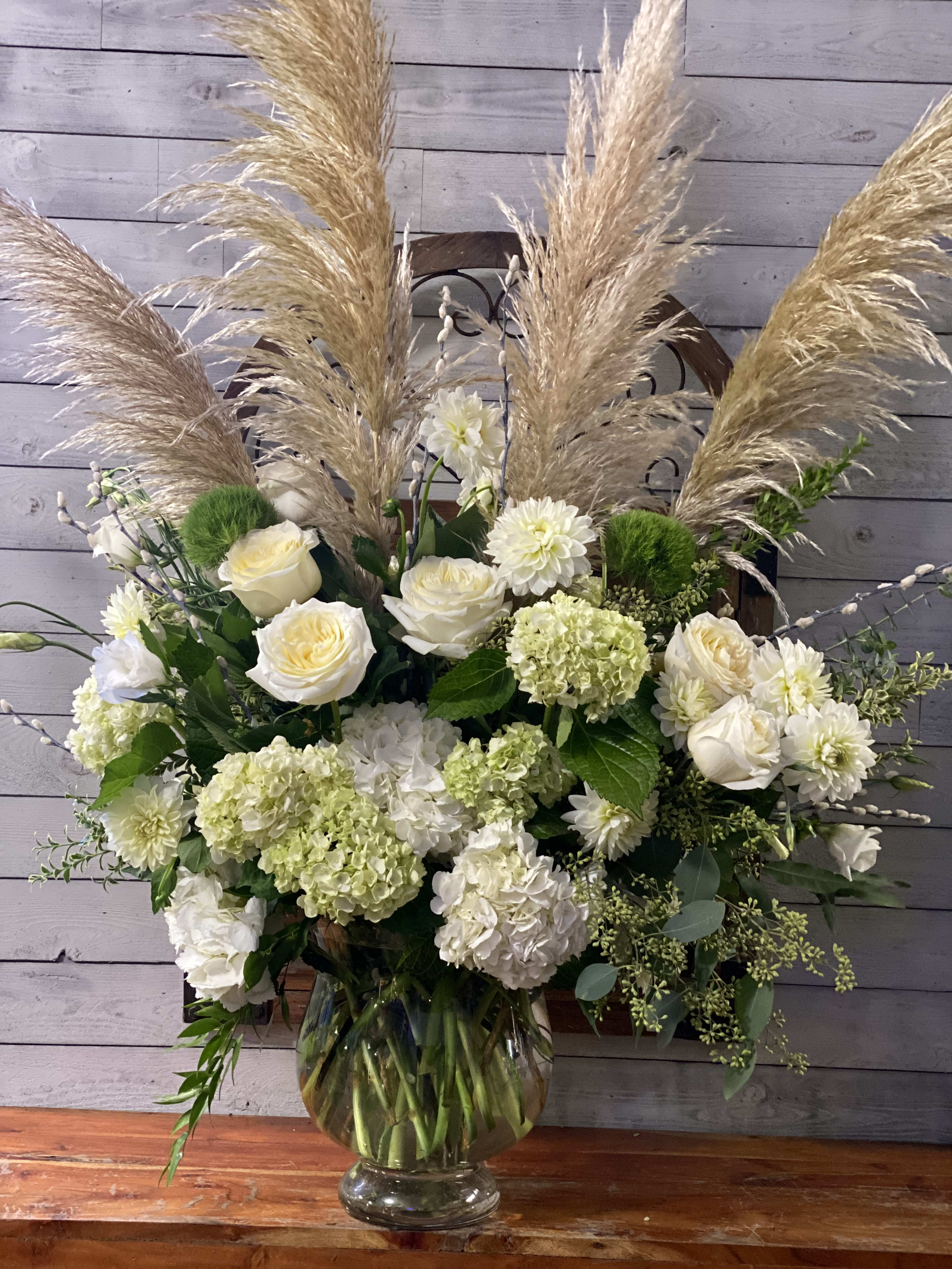 White floral arrangement with pampas grass in a glass vase