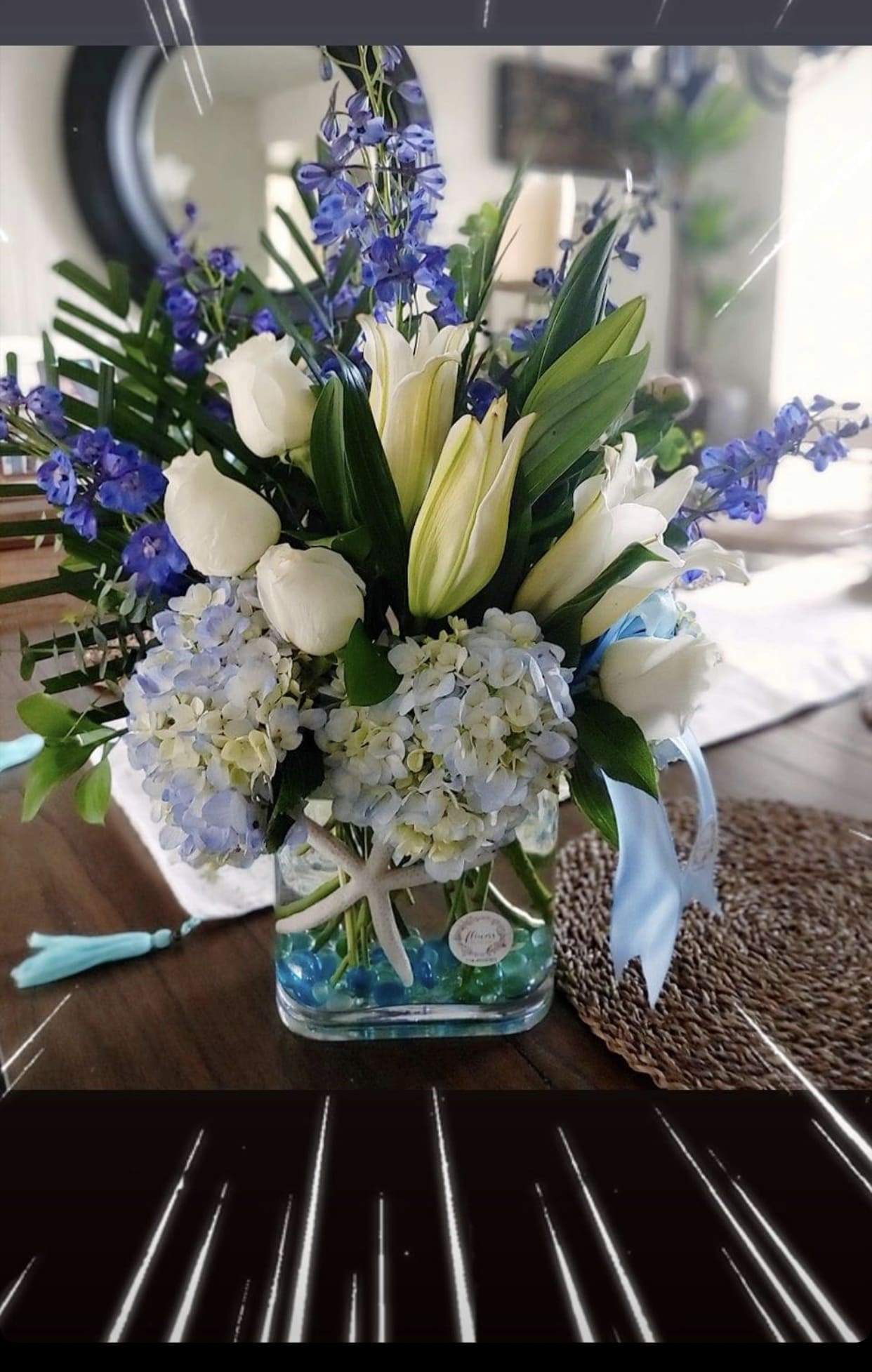 White tulips and blue flowers in a glass vase with blue beads