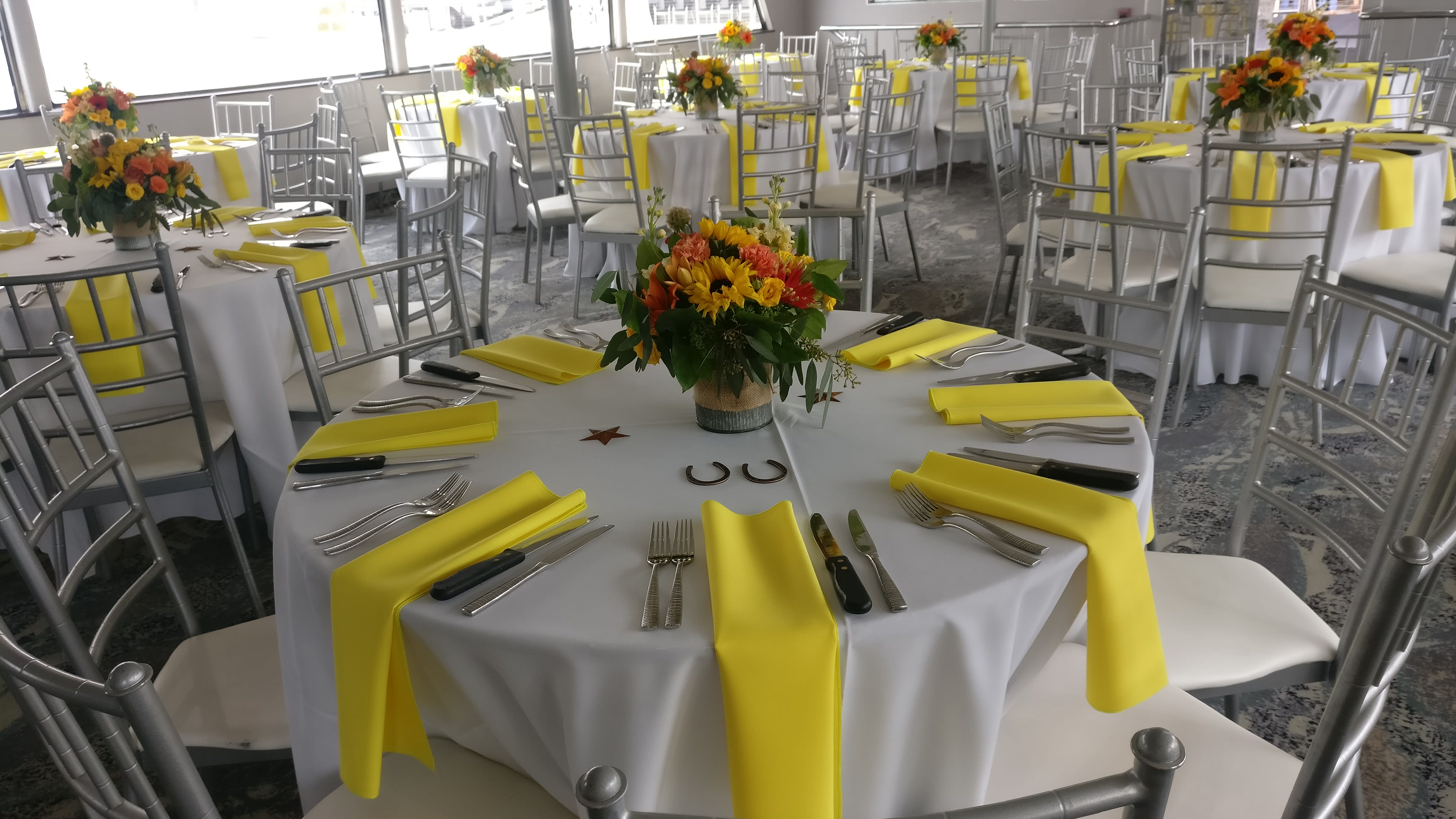 Round banquet tables with yellow napkins and floral centerpieces