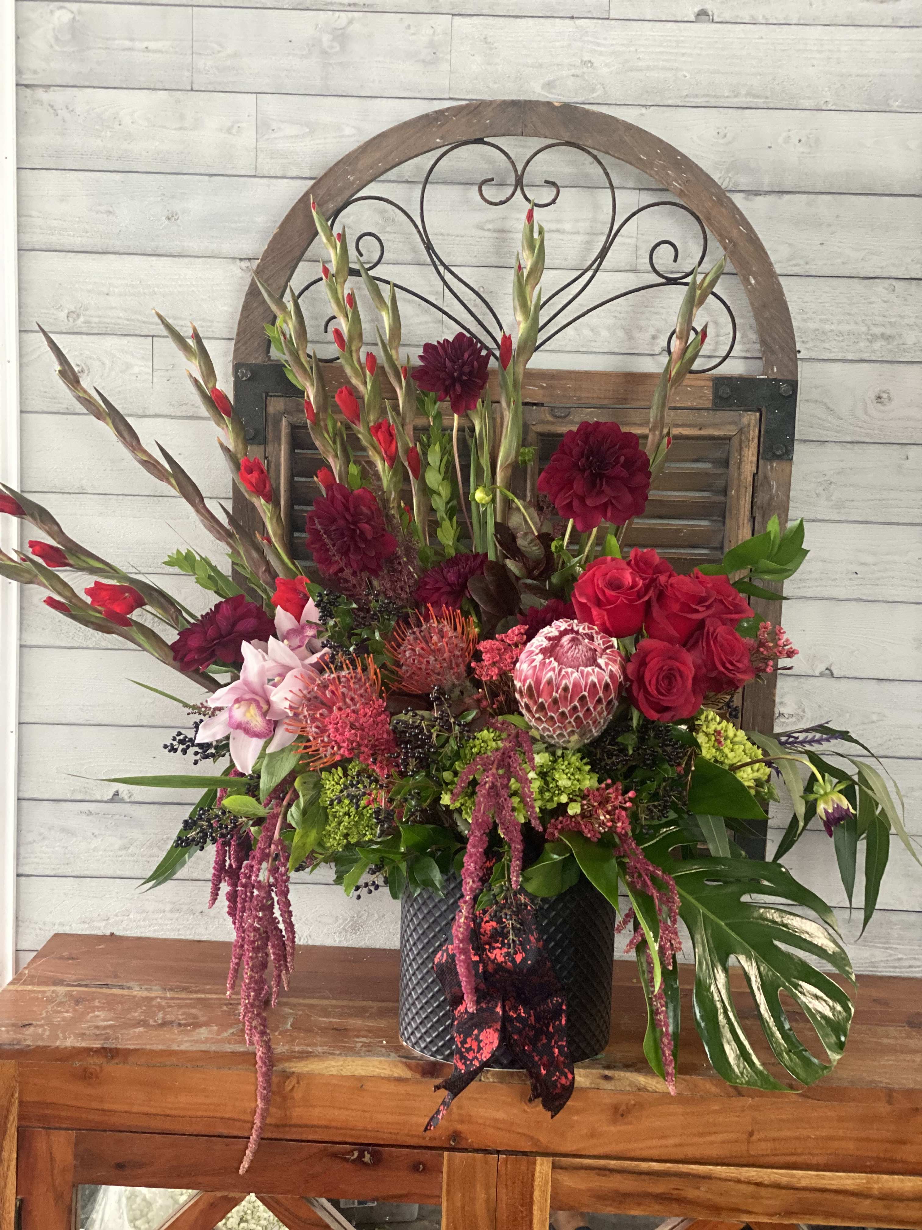 Large mixed floral arrangement in a black vase with red and pink blooms