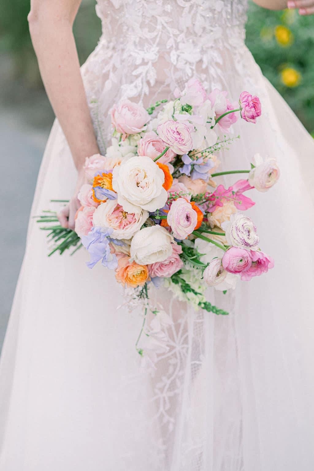 Bride holding a pastel bouquet of pink, white, and orange flowers