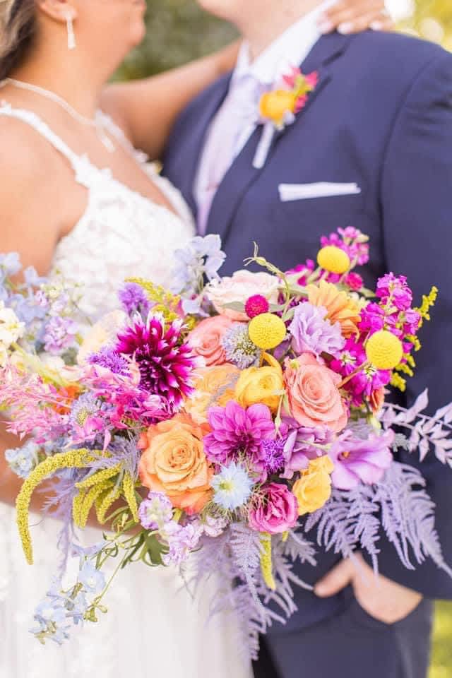 Bride and groom holding a colorful wedding bouquet
