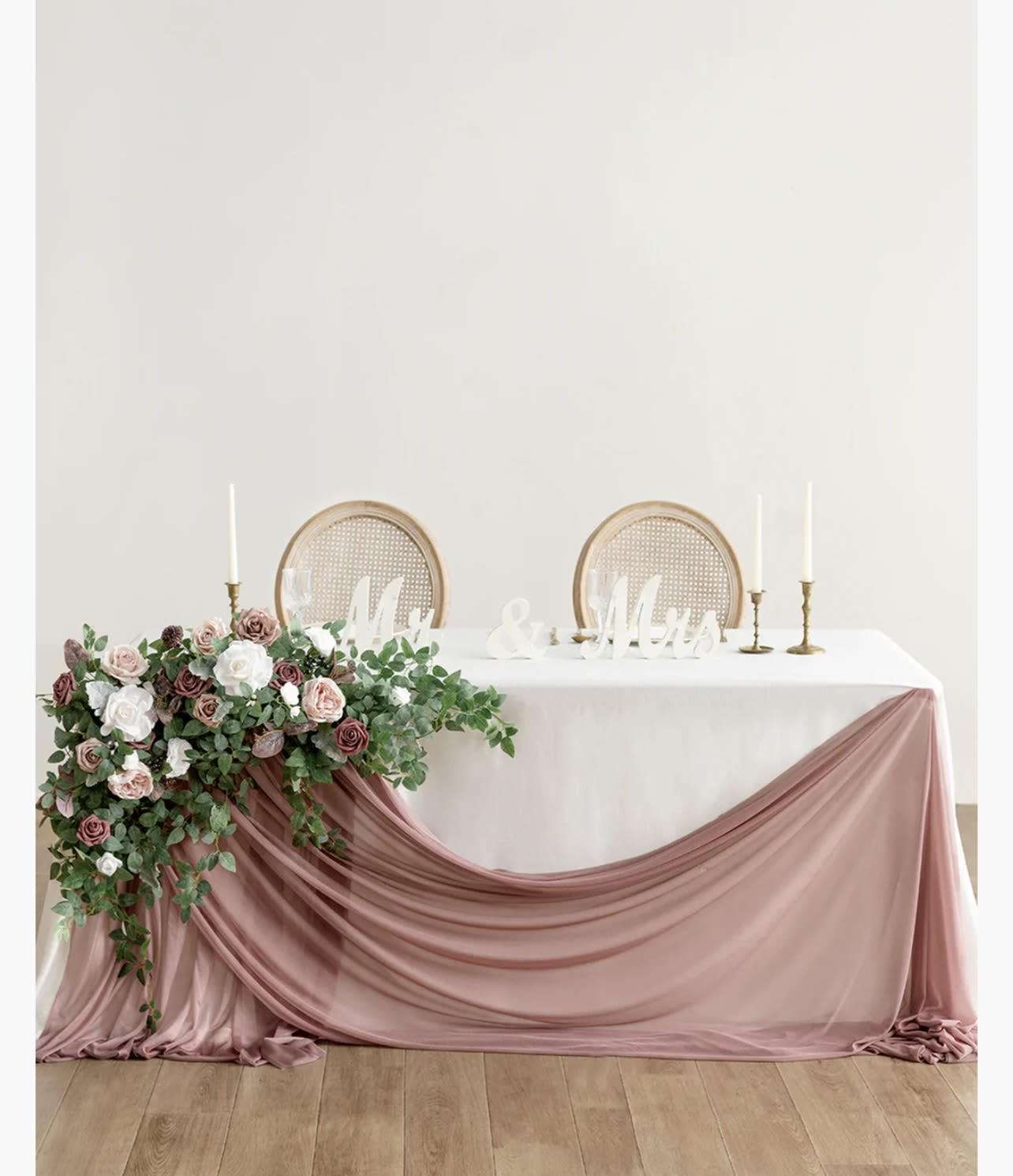 Wedding table with pink floral arrangement and draped blush fabric