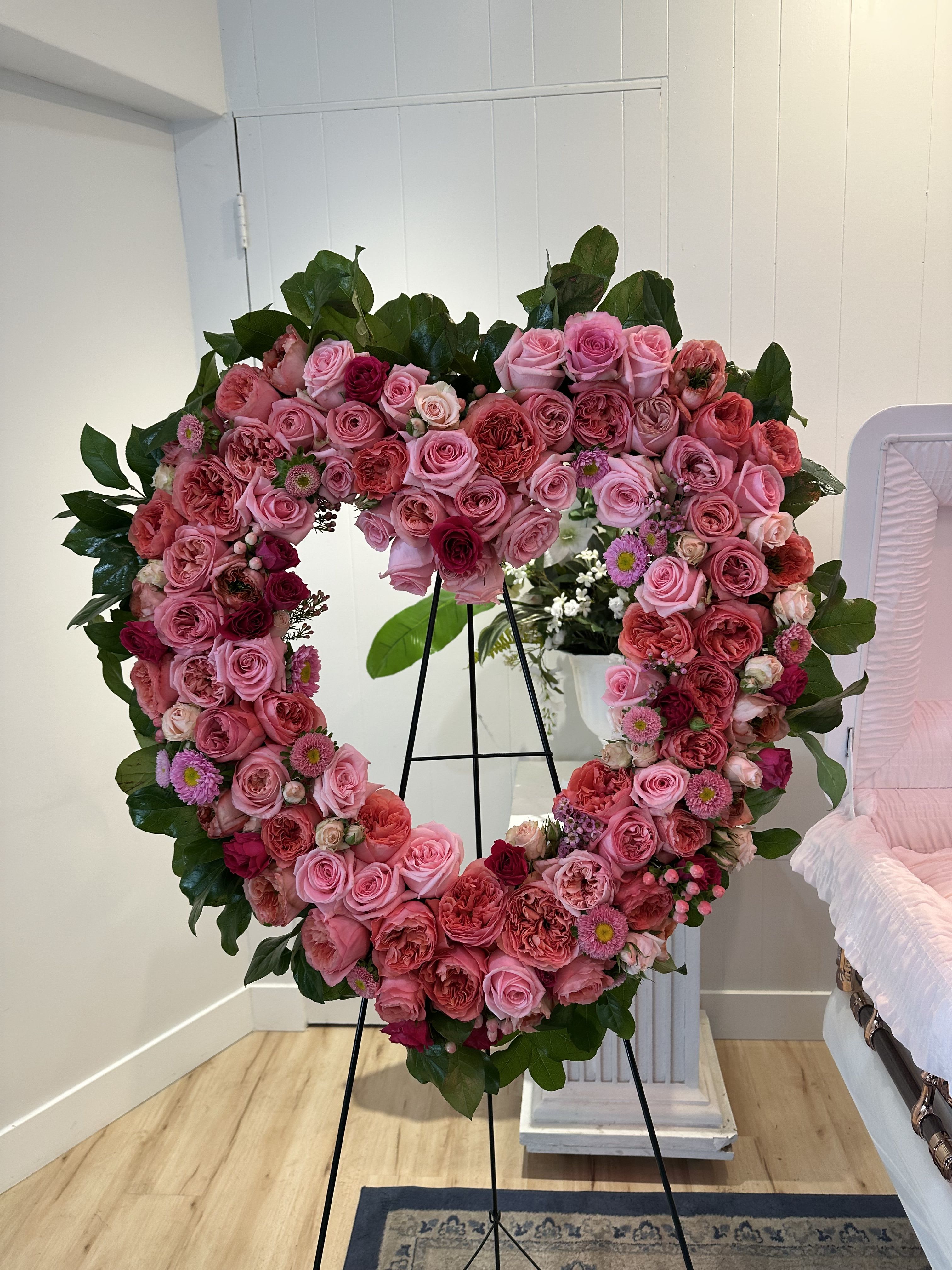 Heart-shaped floral wreath of pink and red roses on a stand