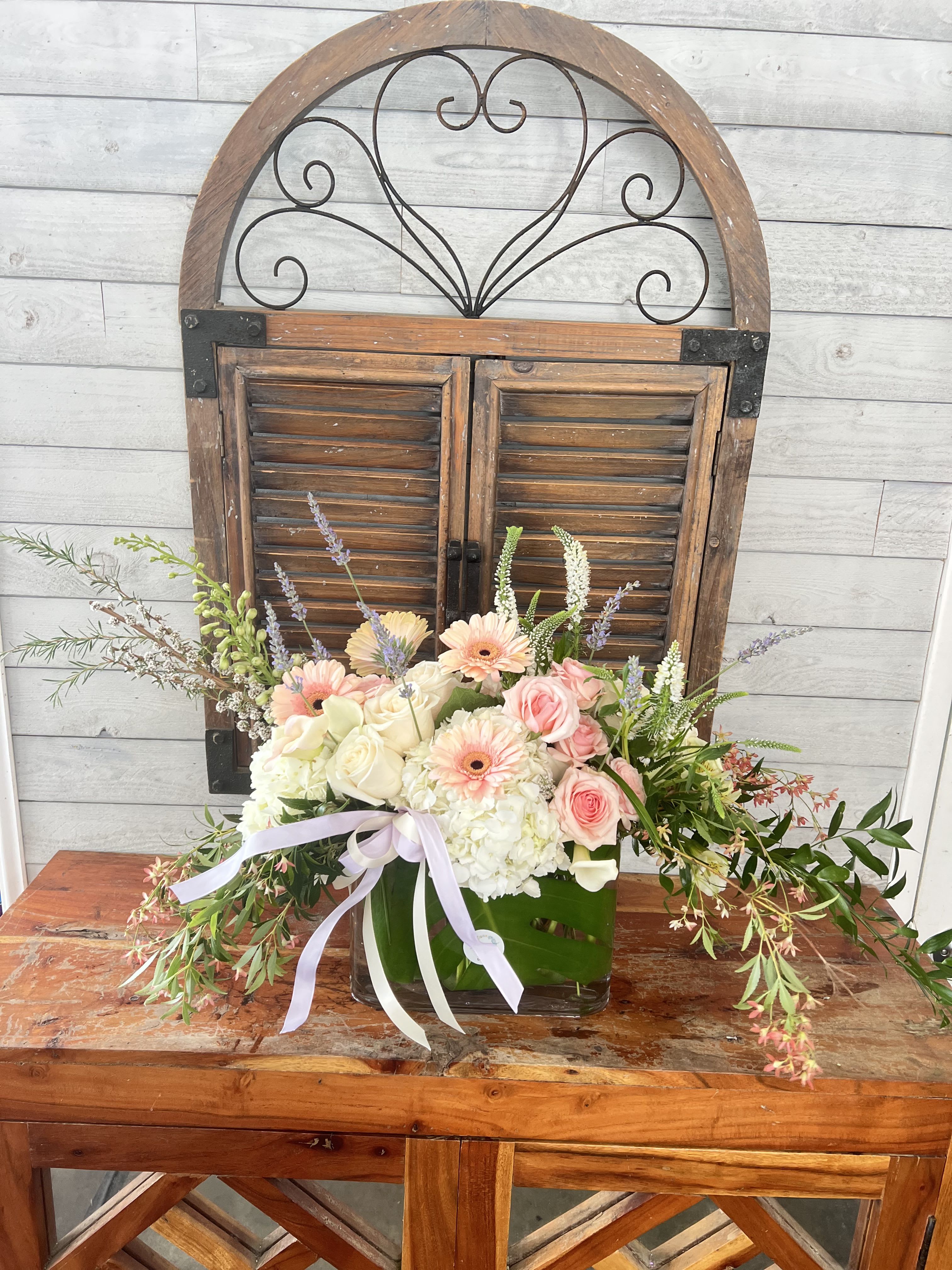 Pastel flower arrangement in a glass vase with a ribbon bow