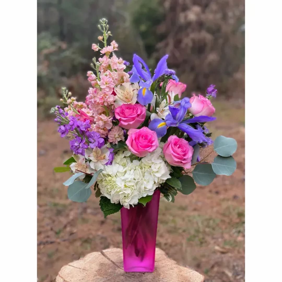 Pink roses and purple flowers in a tall magenta vase