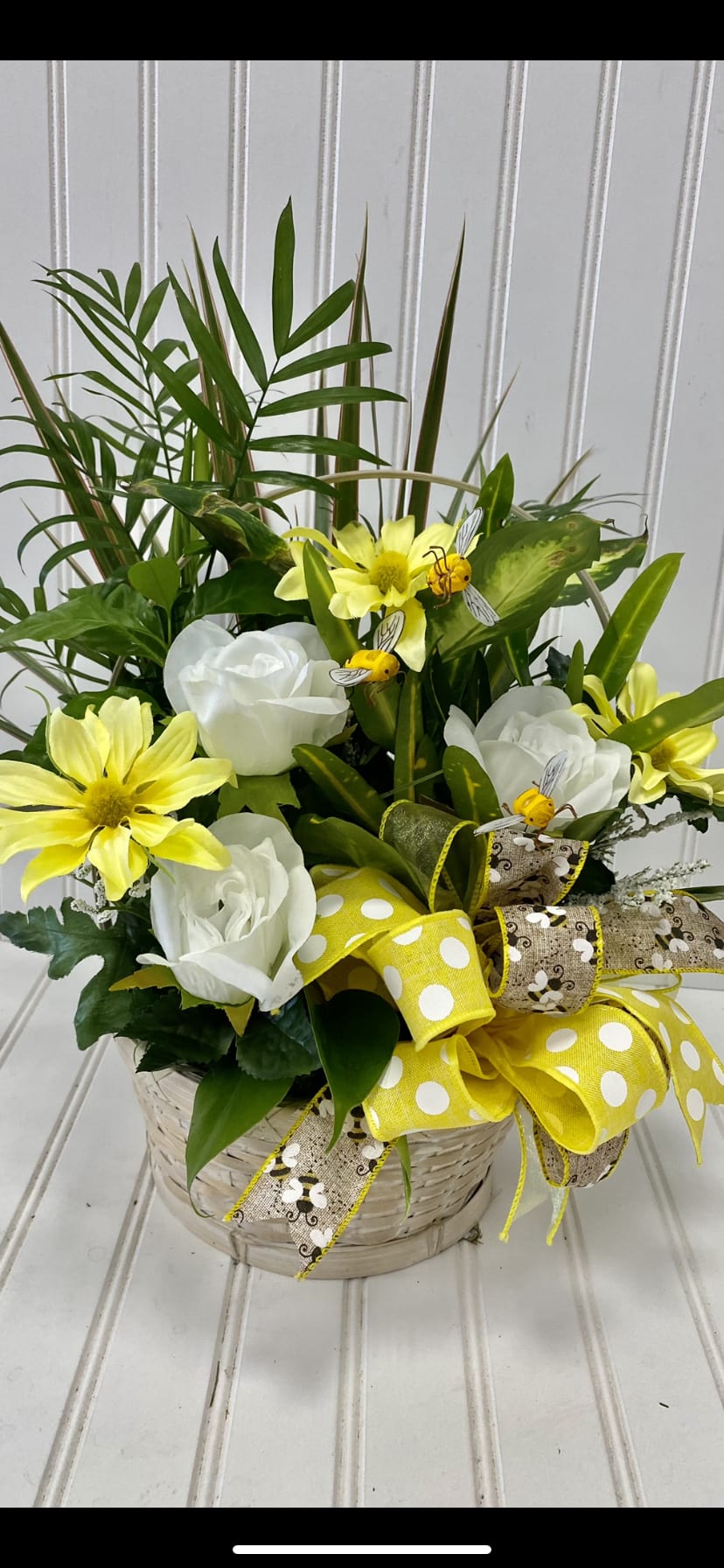 Basket arrangement with white roses, yellow daisies, and a large yellow ribbon