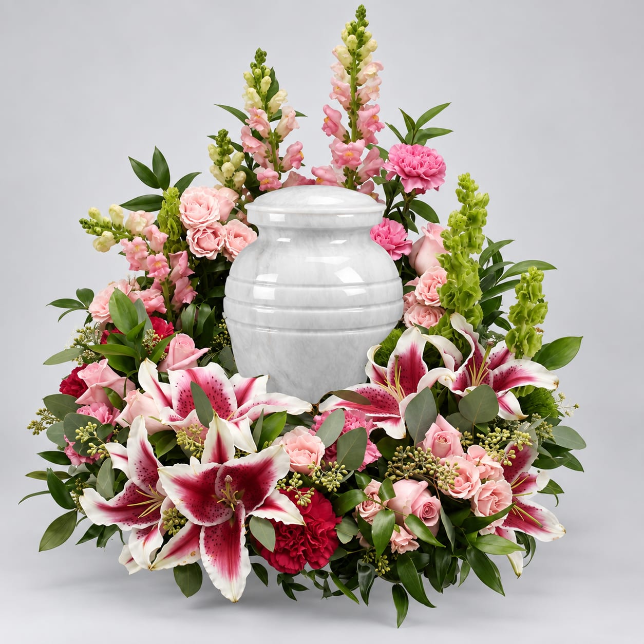 Pink and white floral arrangement surrounding a white urn