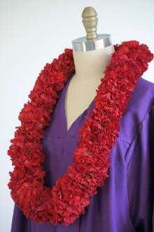 Red flower lei draped over a purple garment on a dress form