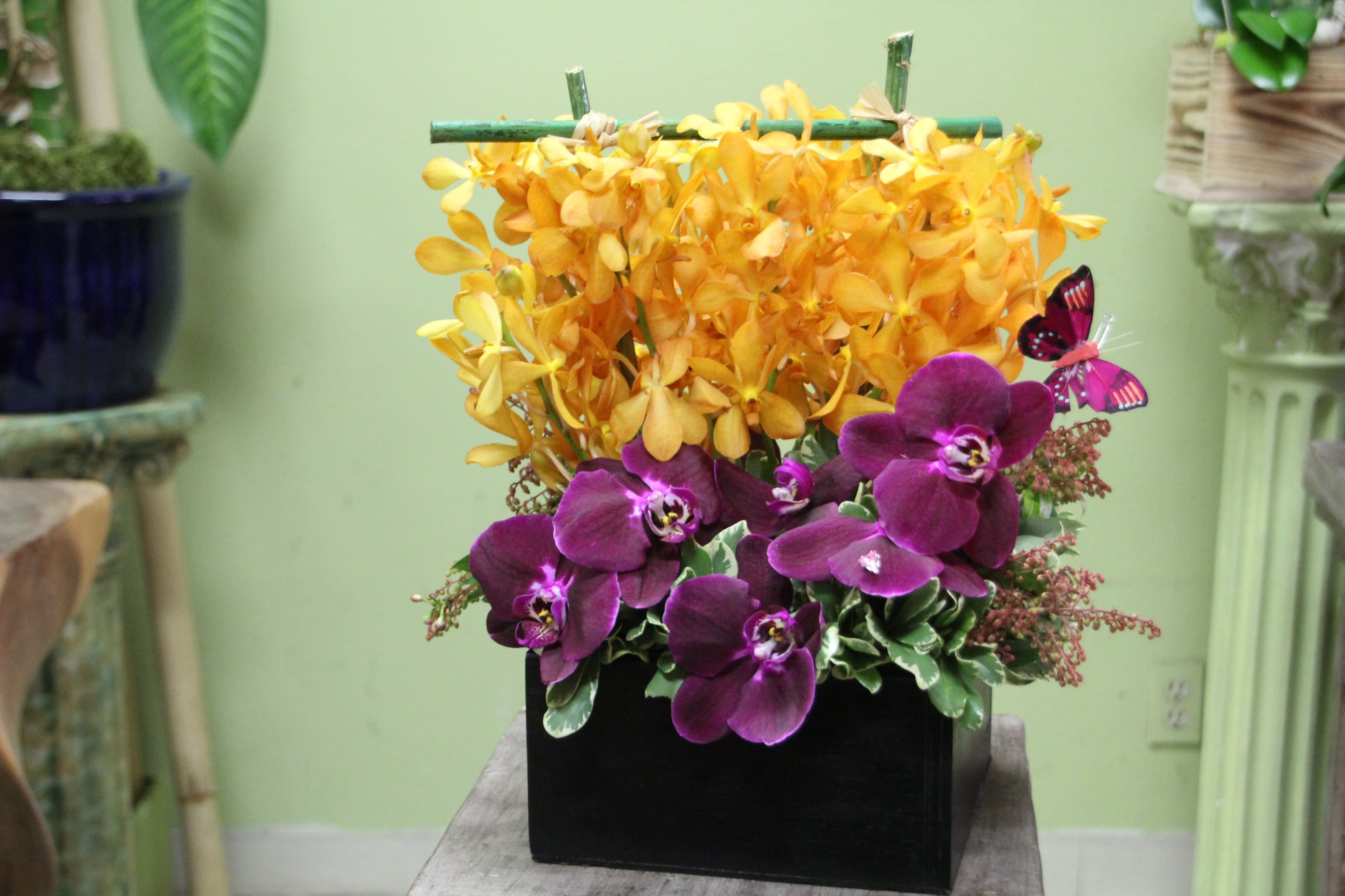 Purple orchids and yellow flowers in a black rectangular container