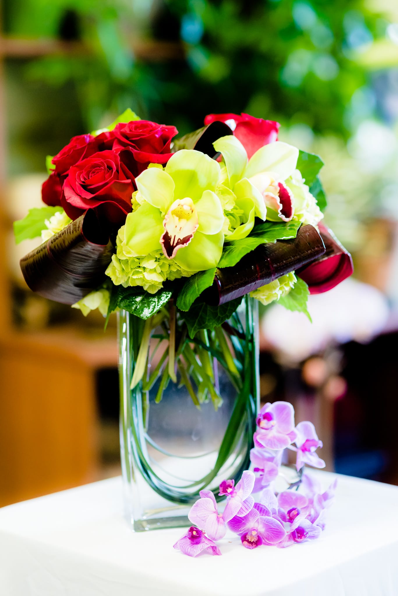 Bouquet of red roses and green orchids in a glass vase