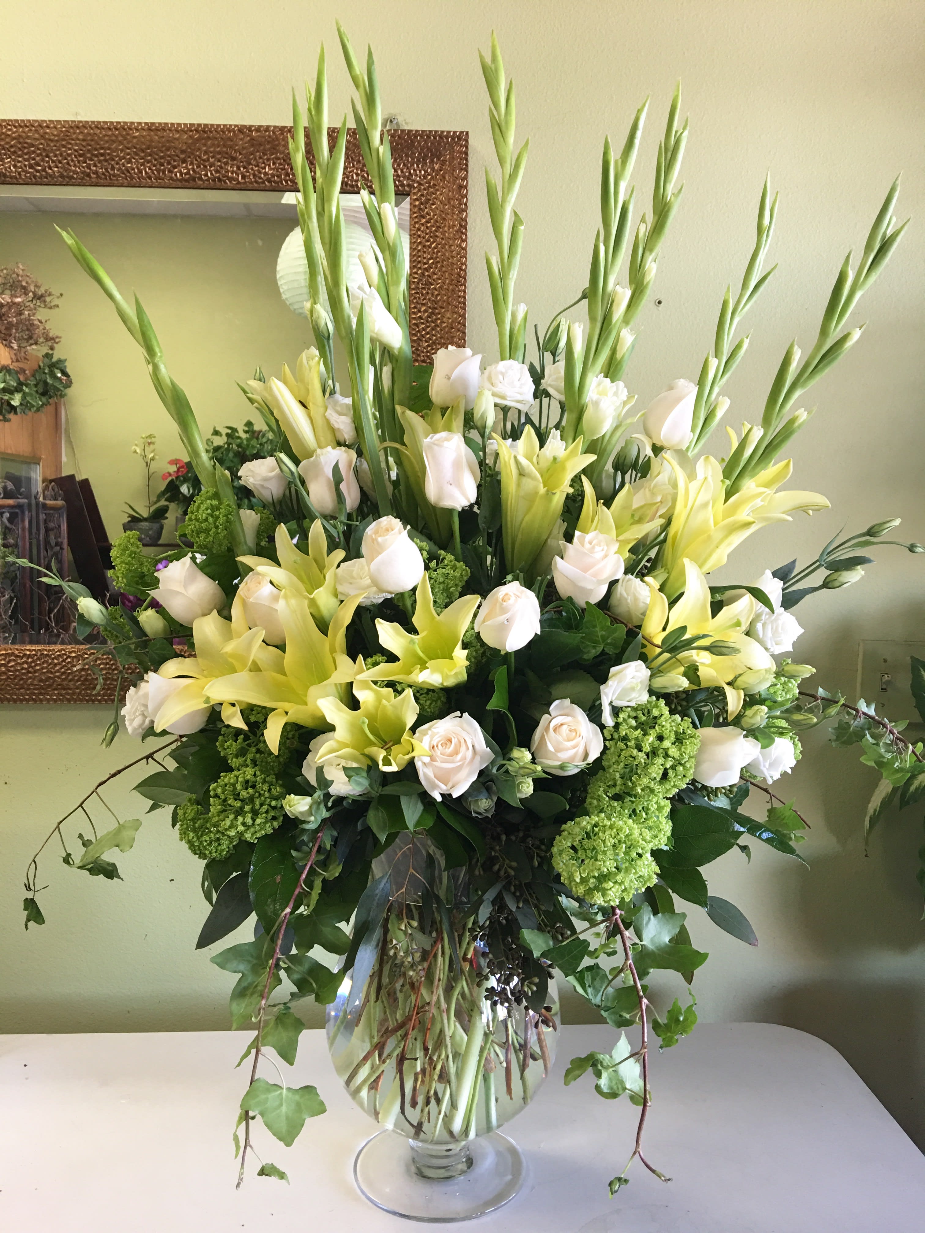 Tall bouquet of white roses and yellow lilies in a glass vase