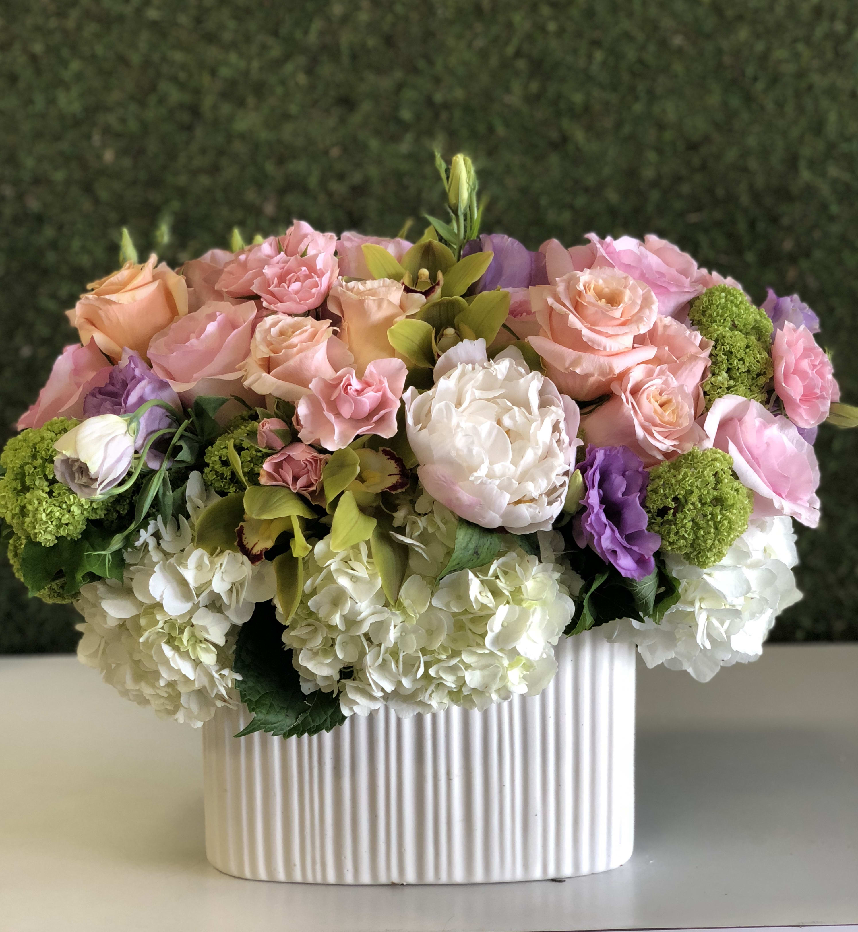 Pink and peach roses with white hydrangeas in a ribbed white vase