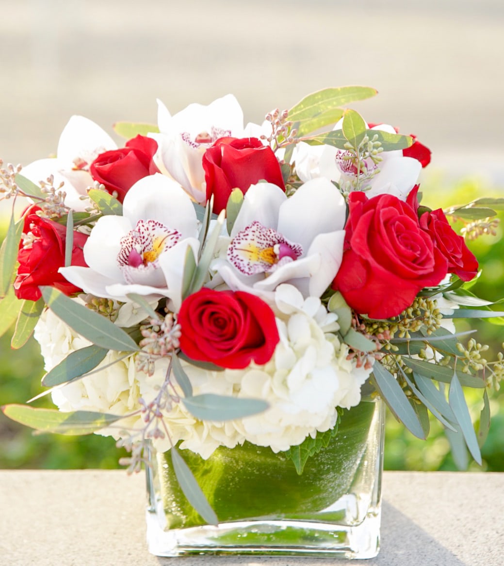 Red roses and white orchids arranged in a clear glass vase