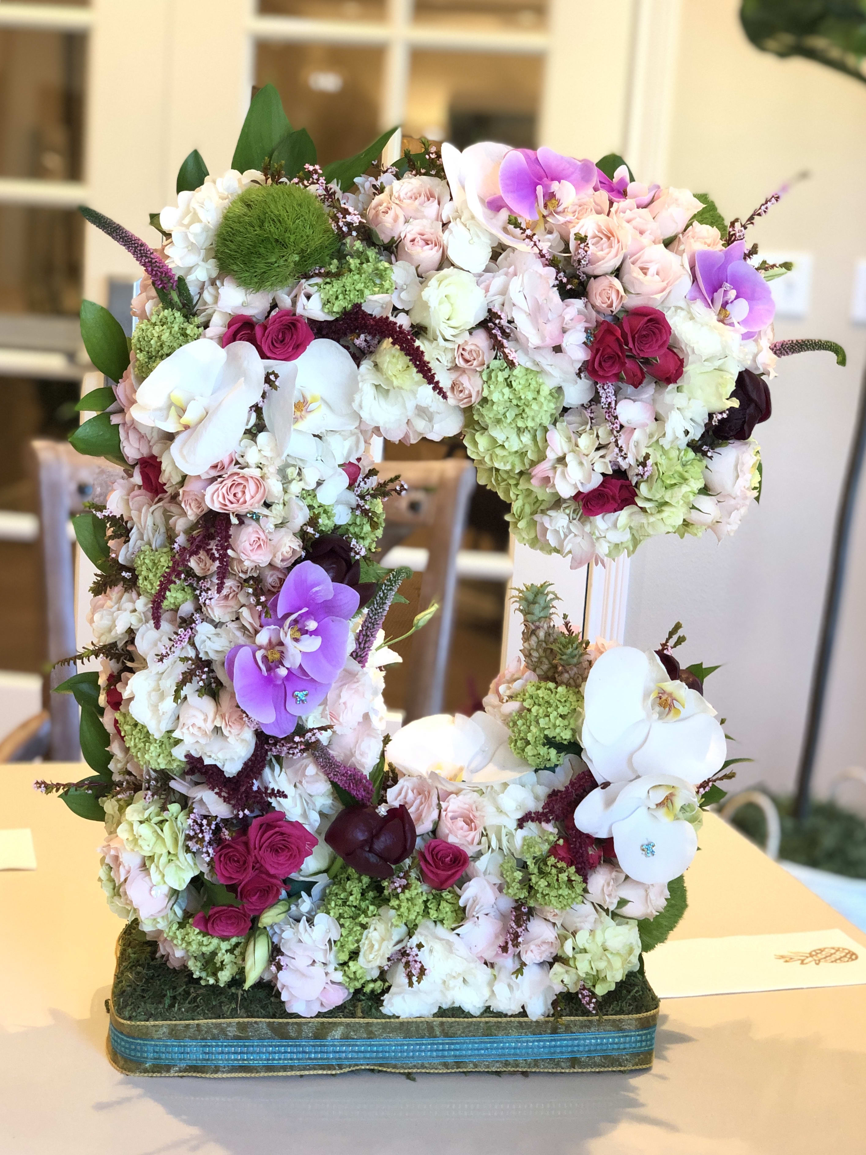 Large floral arrangement shaped like the number 5 with pink, white, and purple blooms
