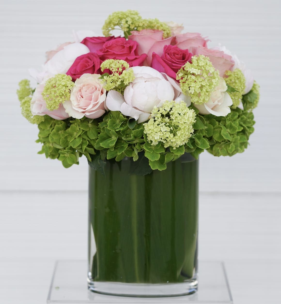Pink and white roses arranged in a green glass vase