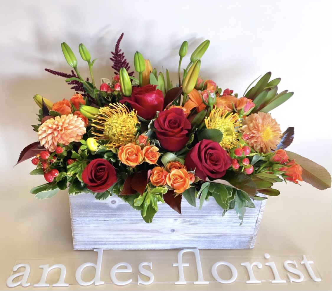 Mixed bouquet of red and orange flowers in a white wooden box