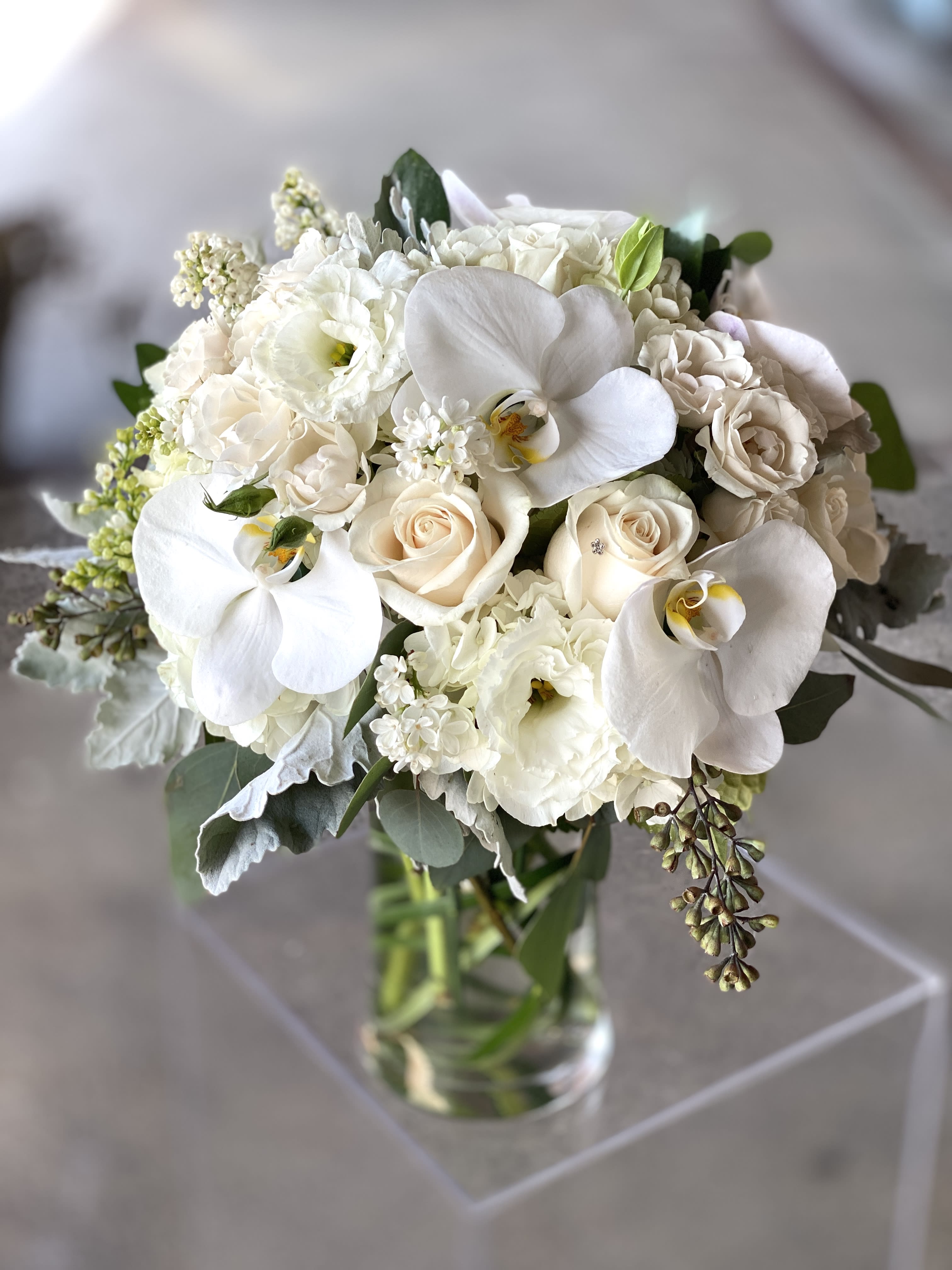 White bouquet of orchids and roses in a clear glass vase