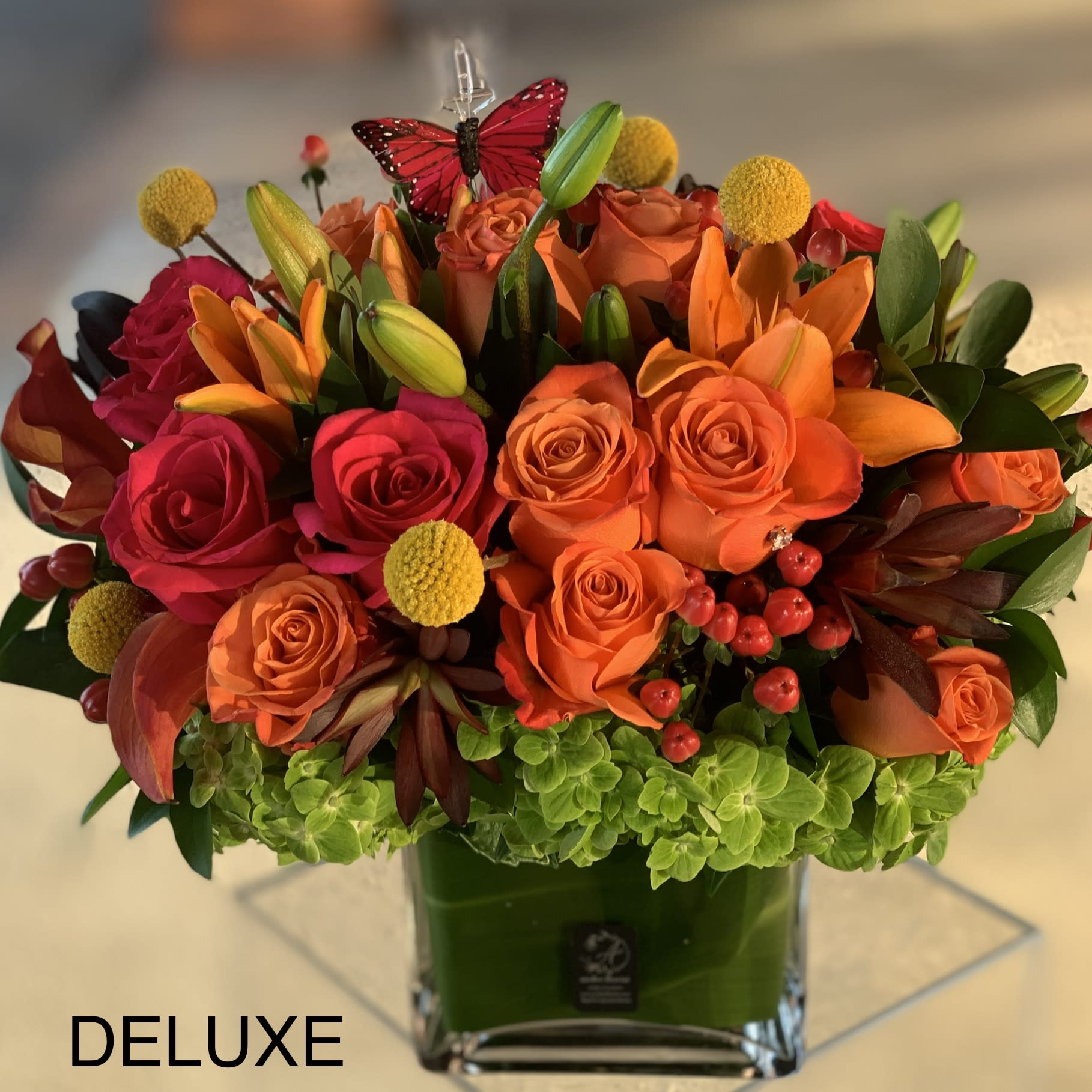 Fall Sunset - Orange, Hot Pink Roses, Calla Lilies, Billy Balls - This abundance of orange and pink hues are a beautiful combination in a glass vase  with green hydrangeas, roses, lilies, callas, billy balls