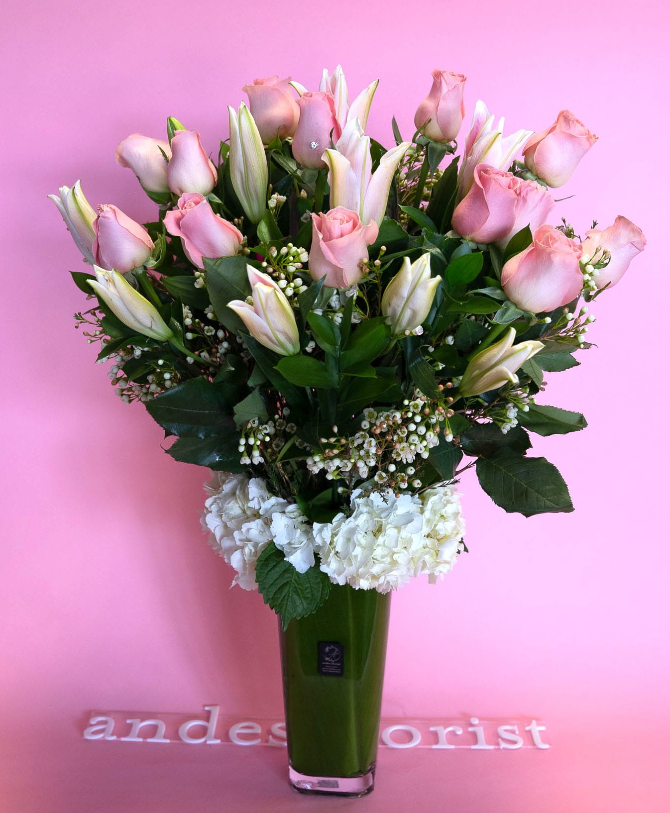 Pink roses and white lilies in a tall green vase
