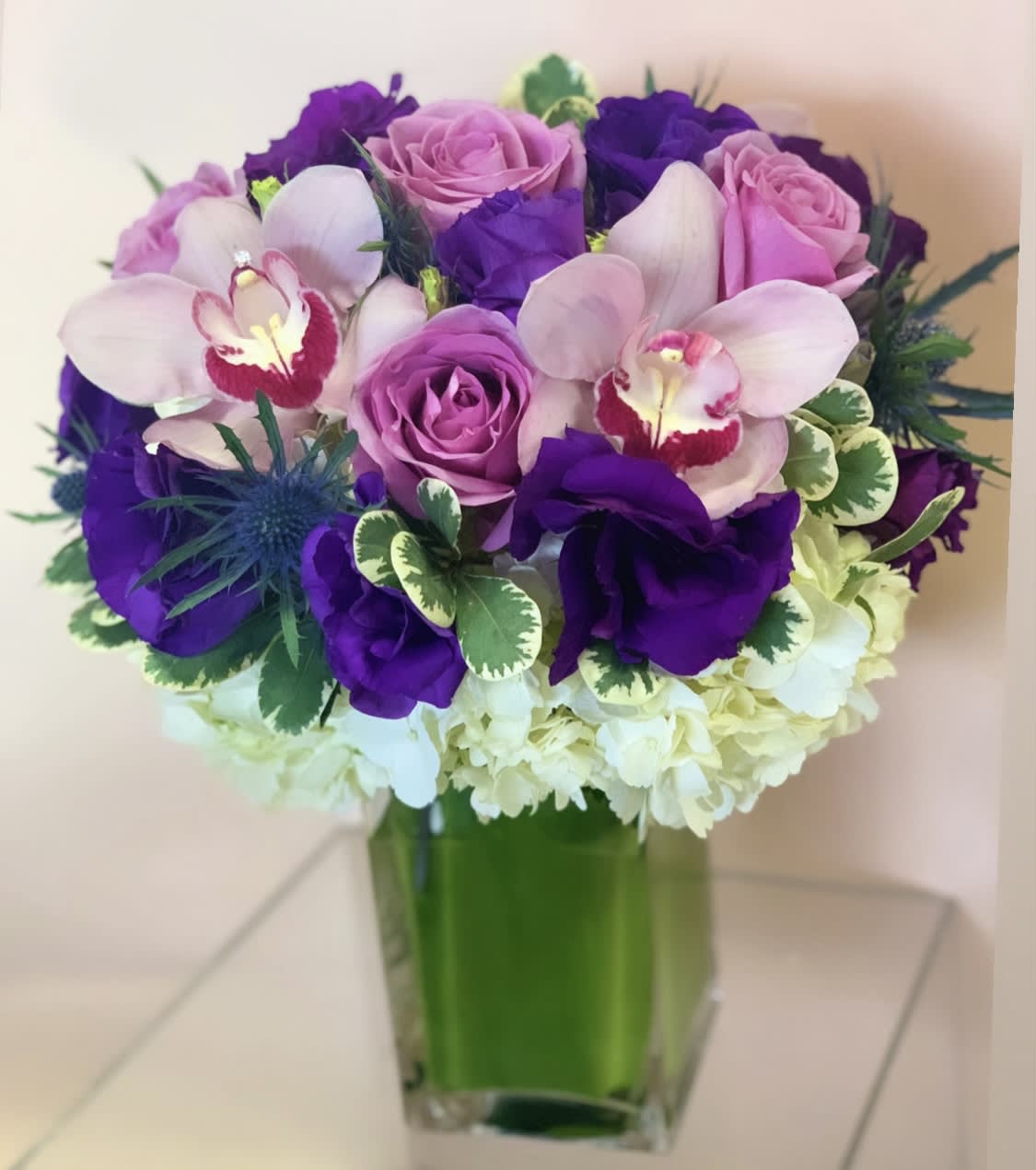 Purple and pink bouquet in a square glass vase