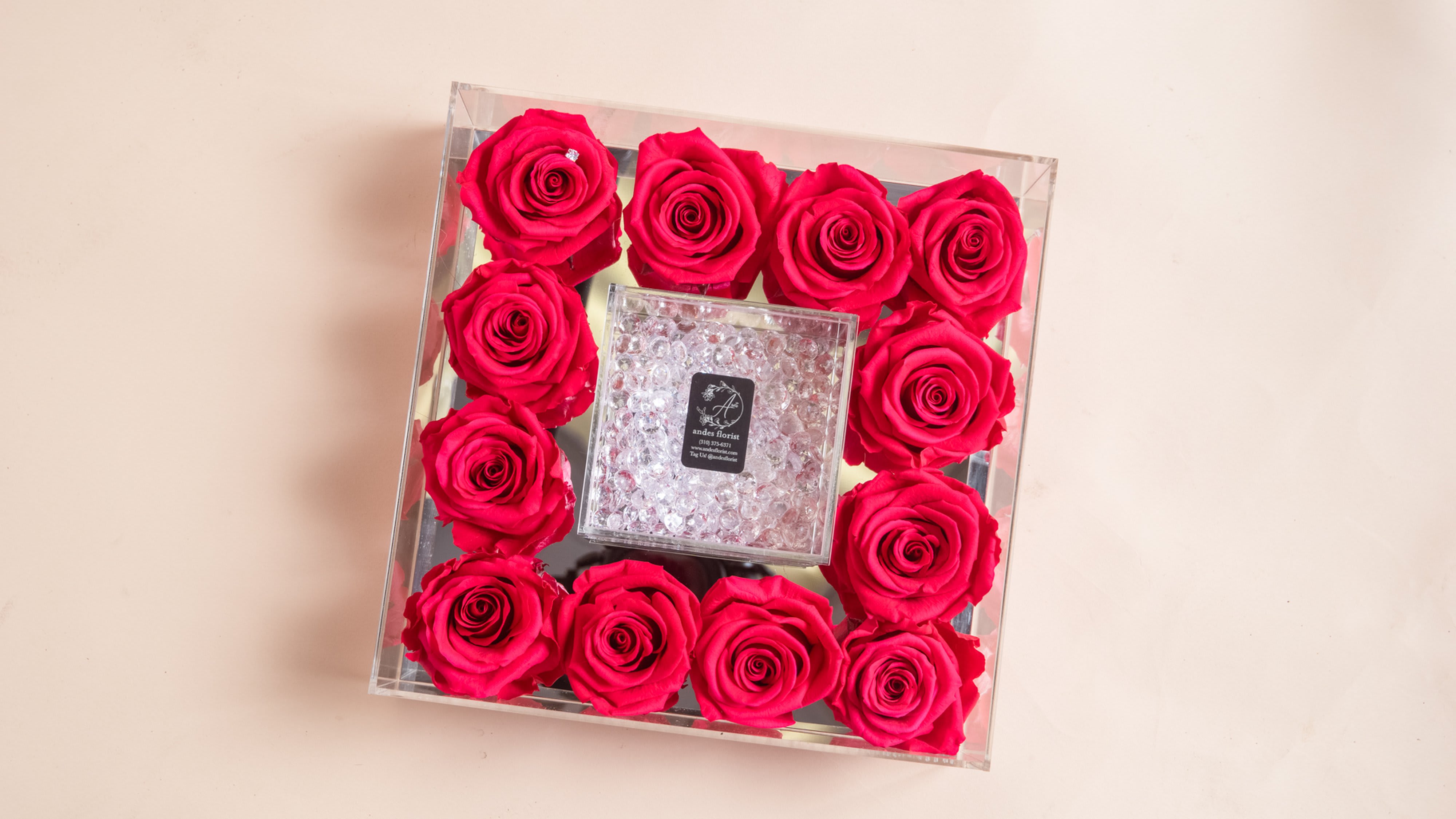 Square clear box filled with hot pink roses around a crystal center