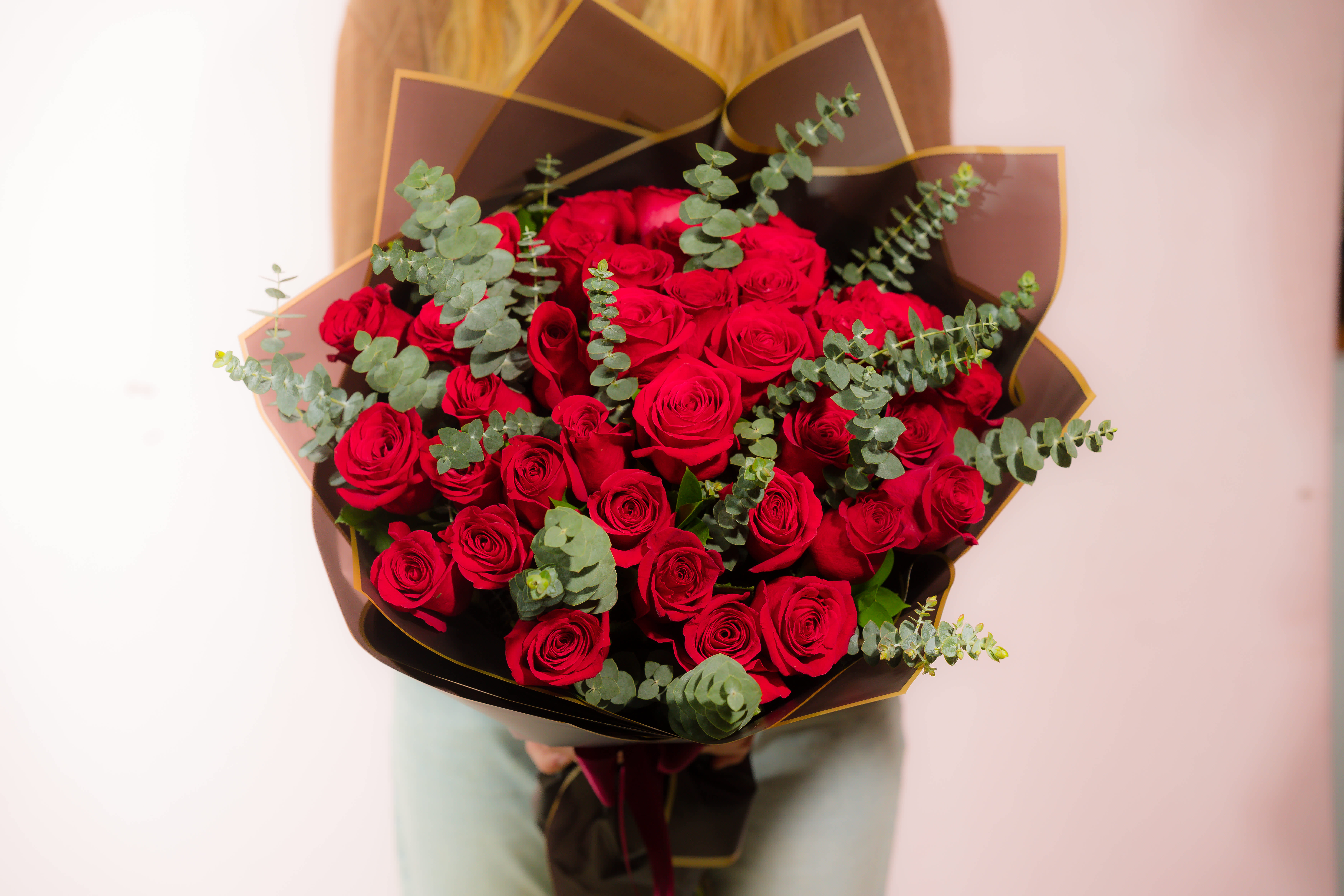 Bouquet of red roses with eucalyptus in dark wrapping