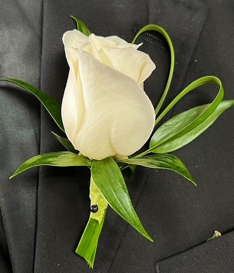 White rose boutonniere with green leaves on a dark suit