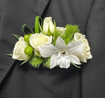 White rose and orchid boutonniere with green accents on a dark suit