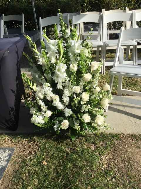White floral arrangement with roses and tall blooms at an outdoor ceremony