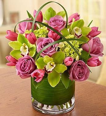 Isabel - Lots of lavender flowers! Orchids, Roses, Tulips - If all the little things they do make you smile, return the favor with this truly original arrangement. Our romantic mix of lavender roses, Cymbidium orchids and tulips is artistically designed with accents of lily grass and tropical leaves and arranged inside a sleek glass cylinder vase to keep you on their mind, always.  Arrangement of the freshest lavender roses, Cymbidium orchids, tulips, mini hydrangeas, lily grass, salal and tropical leaves