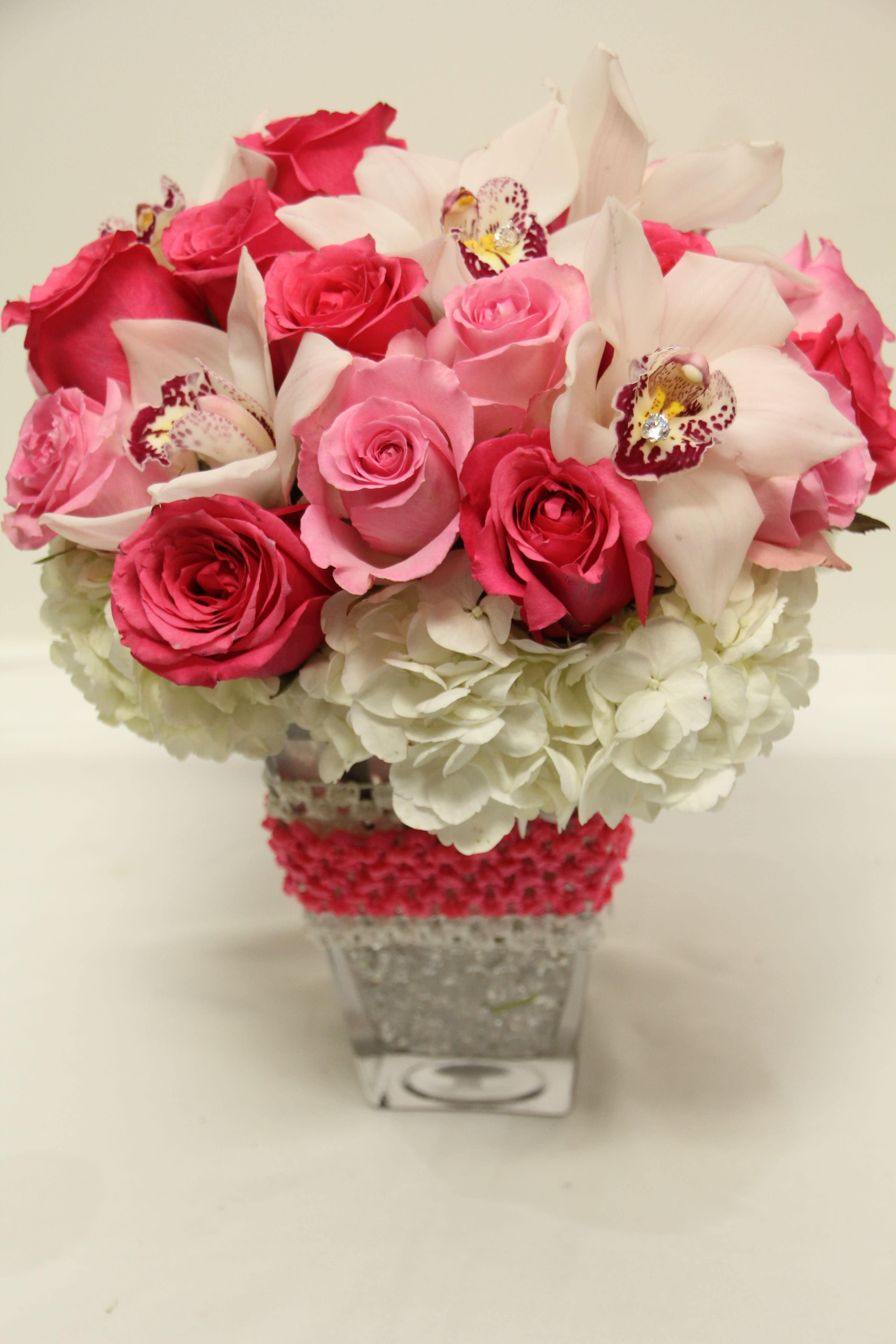 Pink roses and white orchids in a clear square vase