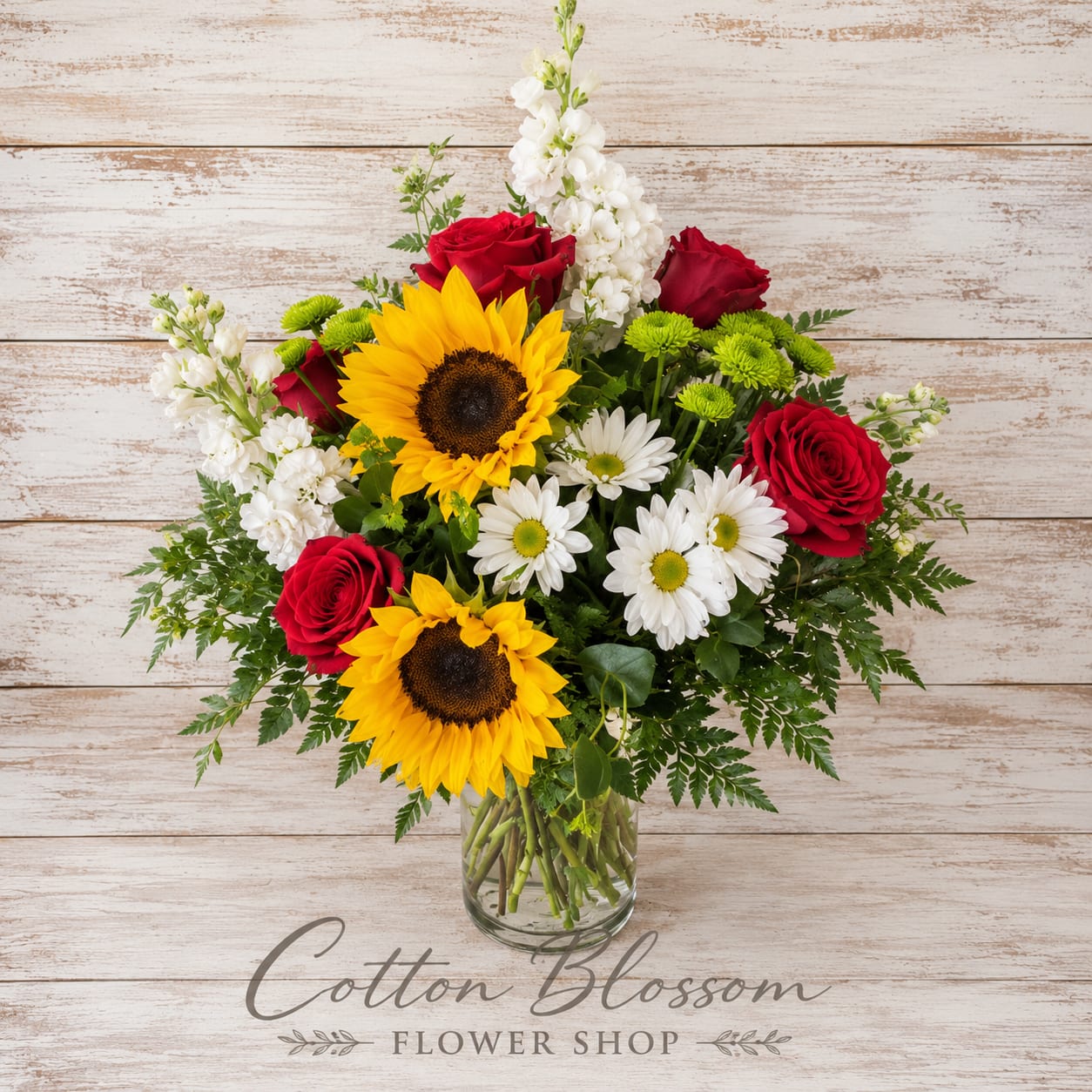 Pure Happiness - Pure Happiness  Pure Happiness is exactly what this joyful bouquet delivers. Bursting with sunny sunflowers, classic roses, cheerful daisies, elegant stock, and lush greenery, this beautiful arrangement is designed to brighten any room and every heart it touches.  Whether you're celebrating a birthday, expressing gratitude, sending warm wishes, or simply reminding someone how much they mean to you, this vibrant arrangement is sure to bring a smile. Full of color, beauty, and happiness, it's the kind of gift that makes an ordinary day feel extraordinary.  Handcrafted in a clear glass vase and designed all around for beauty from every angle.  Flower varieties and colors may vary slightly based on seasonal availability while maintaining the overall style, value, and beauty of the arrangement.