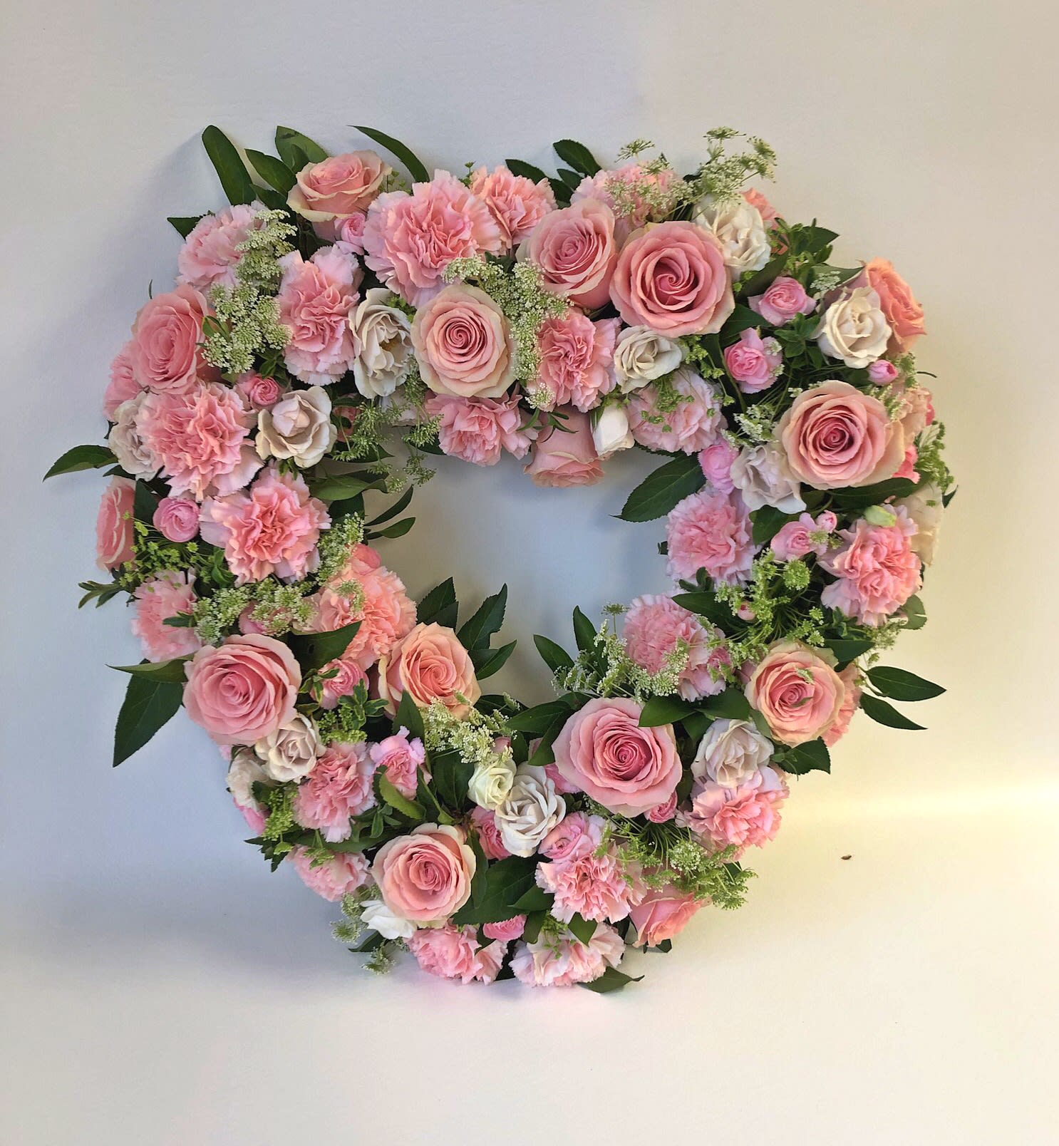 Heart-shaped floral wreath of pink roses and carnations