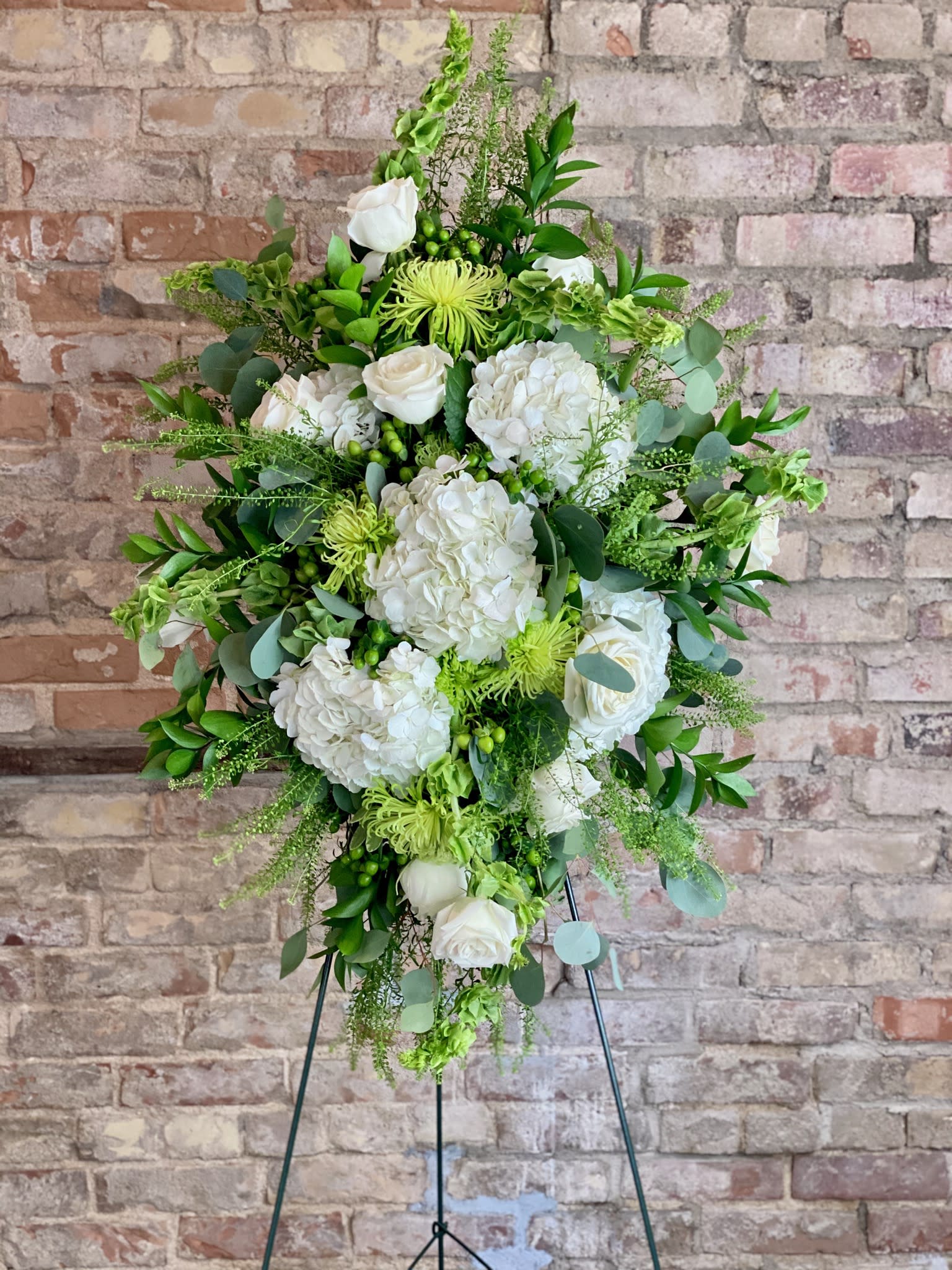 Tall white and green floral standing spray on an easel