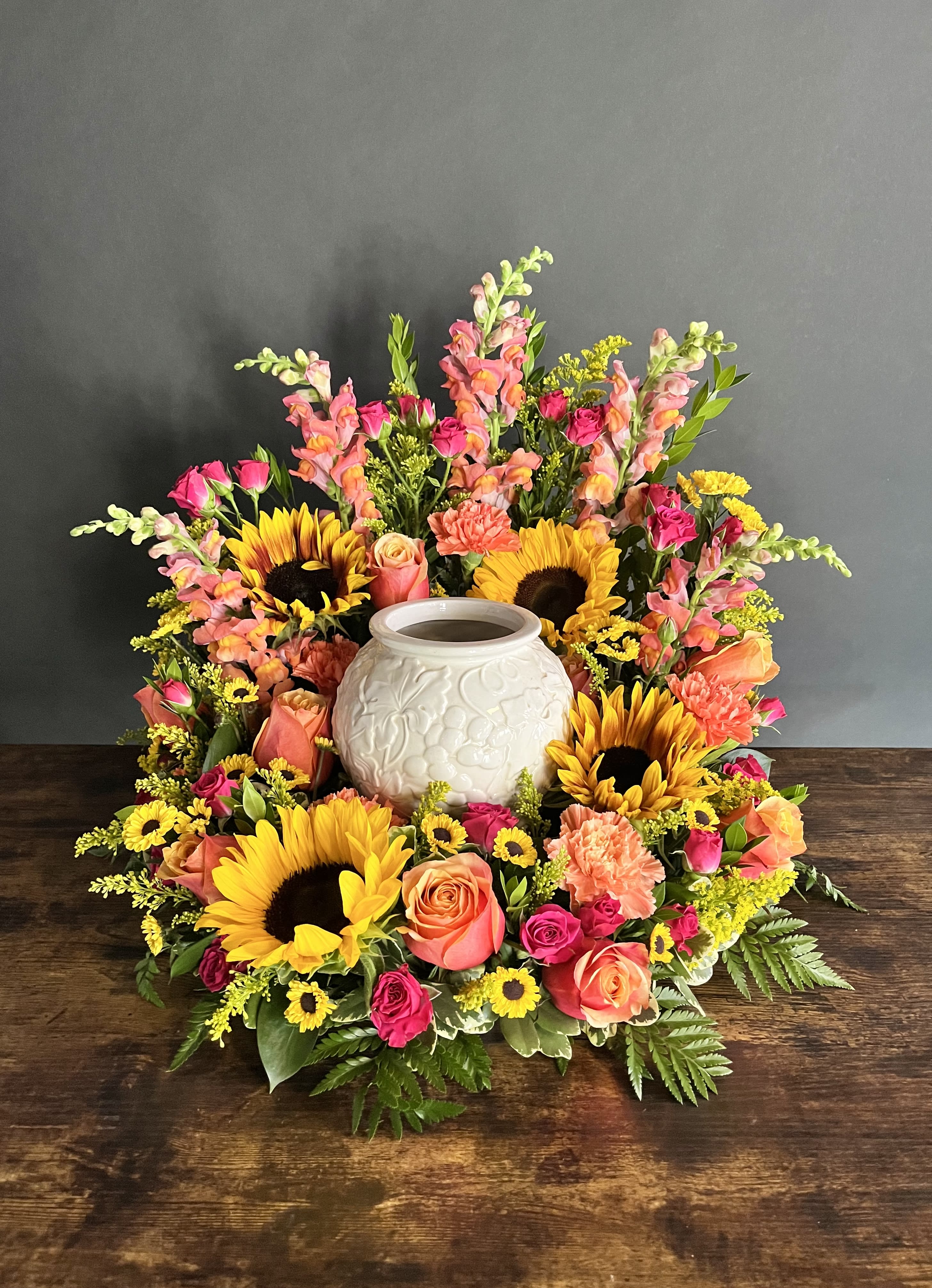 Colorful floral wreath around a white ceramic urn