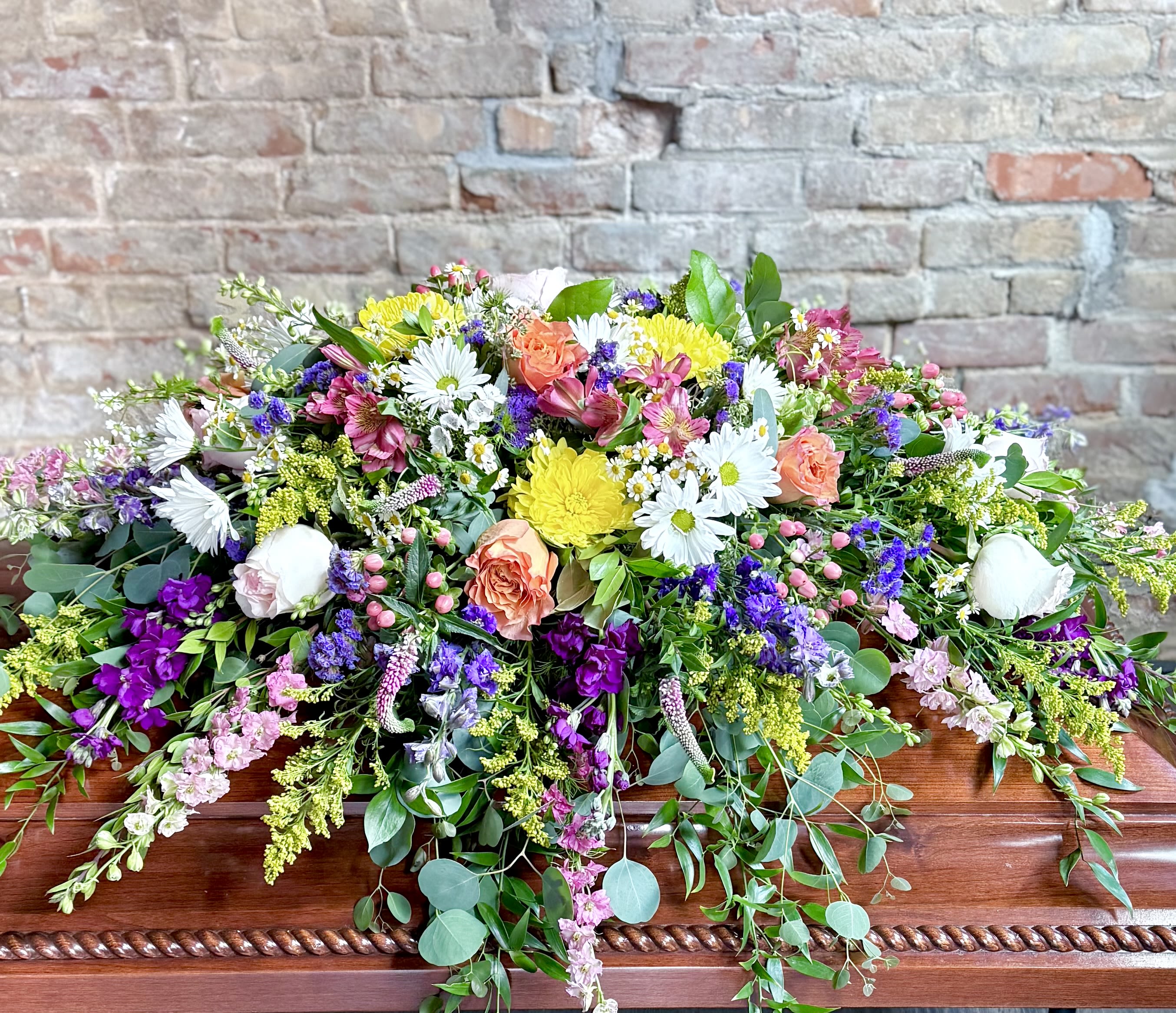 Large casket spray with mixed pink, white, yellow, and purple flowers