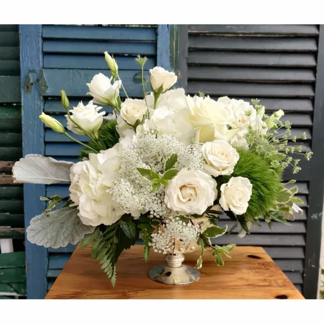 White floral arrangement in a silver pedestal vase