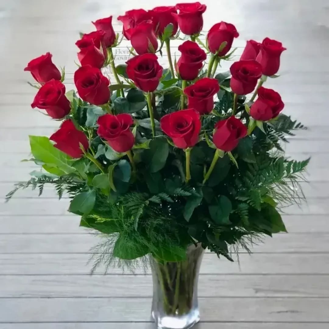 Red roses arranged in a clear glass vase with greenery