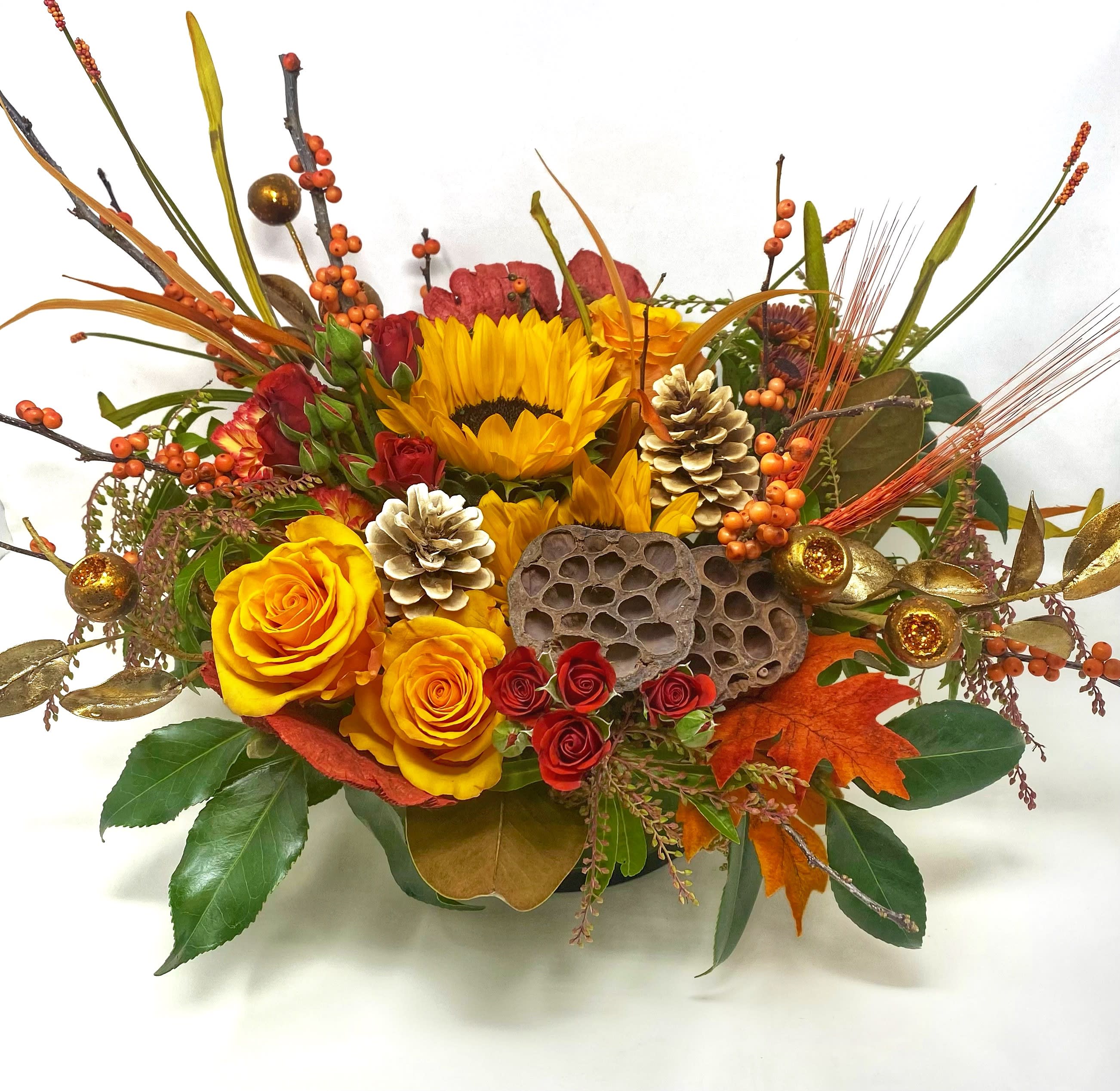 Autumn Elegance Centerpiece - Beautifully arranged bight autumn tones of blooms and texture in a low centerpiece cylinder. Approximately 6 inches high and 22 inches across. Bring the elegance of fall and harvest to your dining table.  