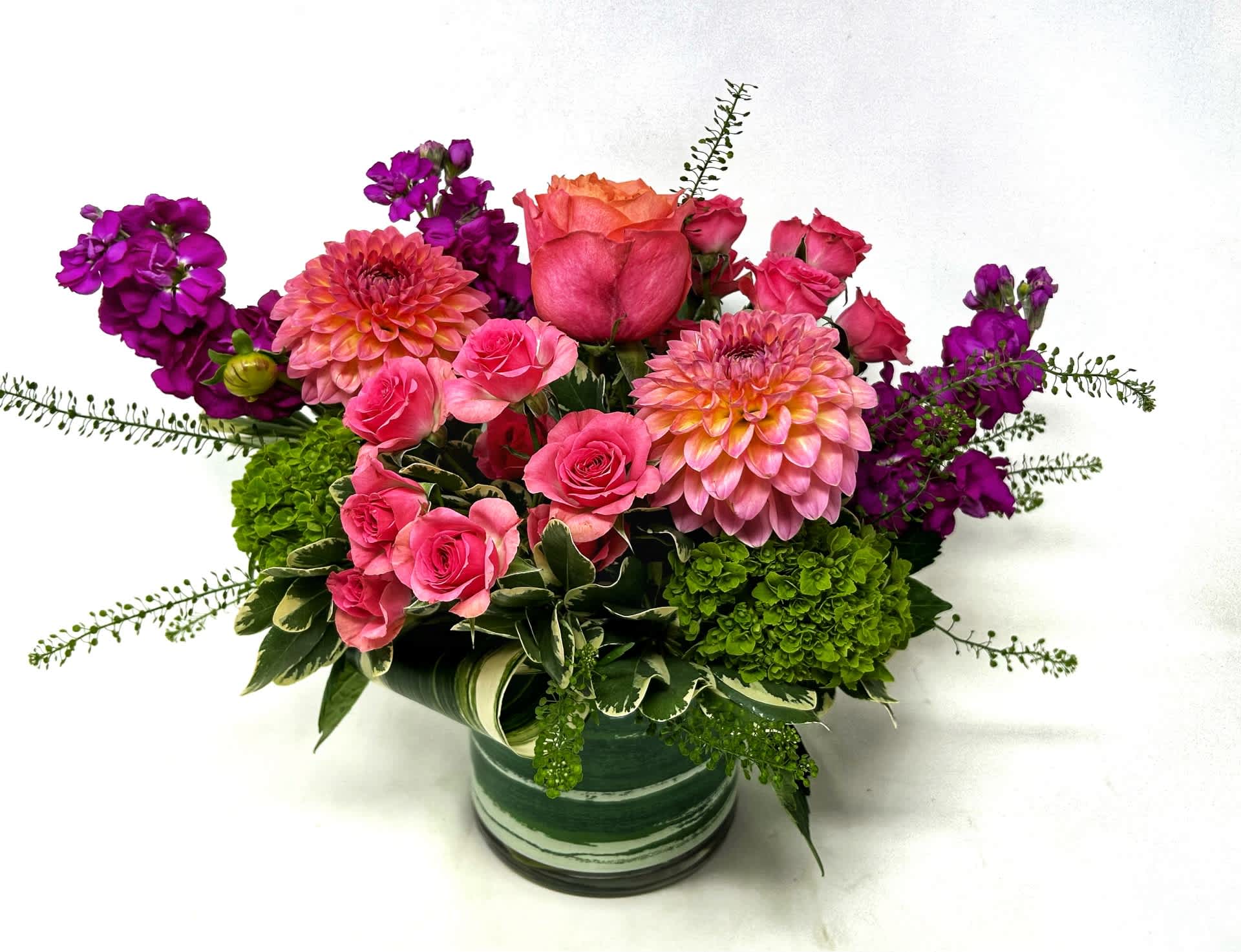 Pink and purple flower arrangement in a green striped vase