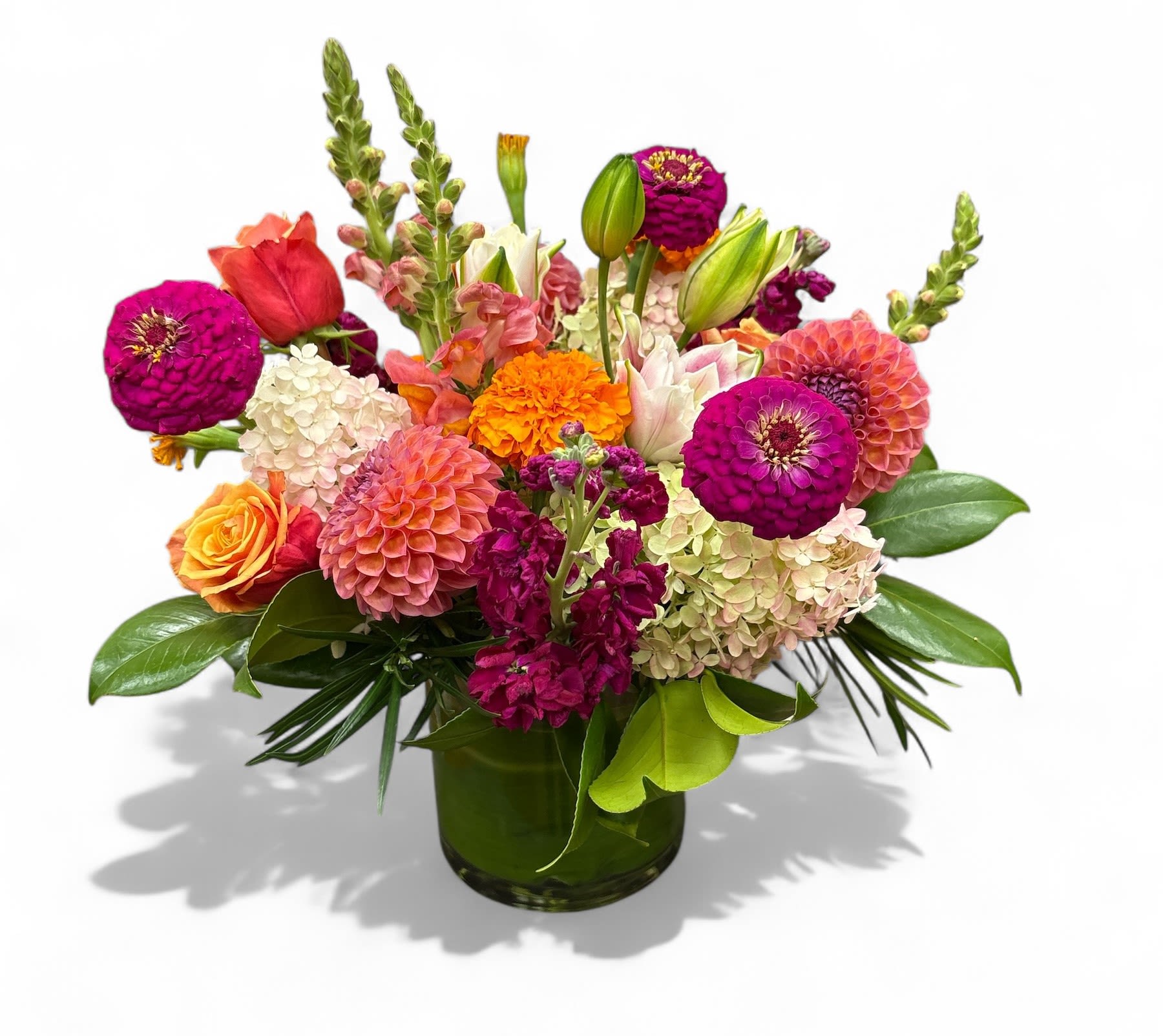 Colorful mixed bouquet in a green glass vase with zinnias and roses